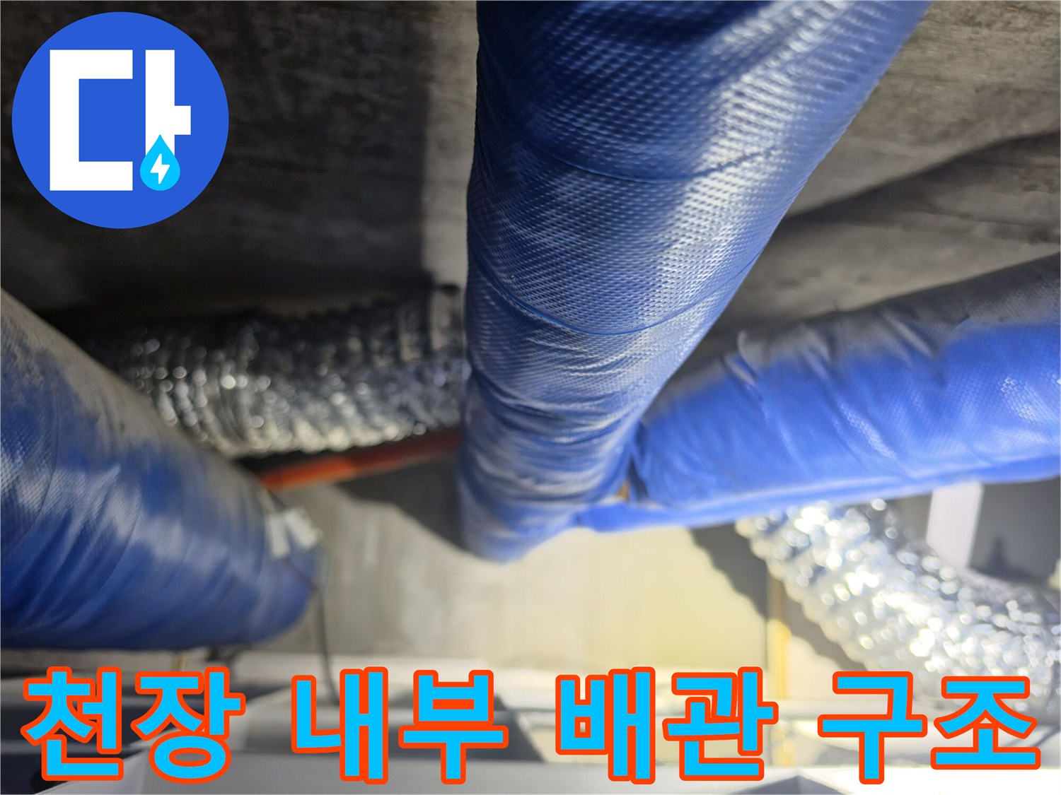 파란색 보온재가 입혀진 배관과 은색 자바라 호스가 설치된 천장 내부 모습