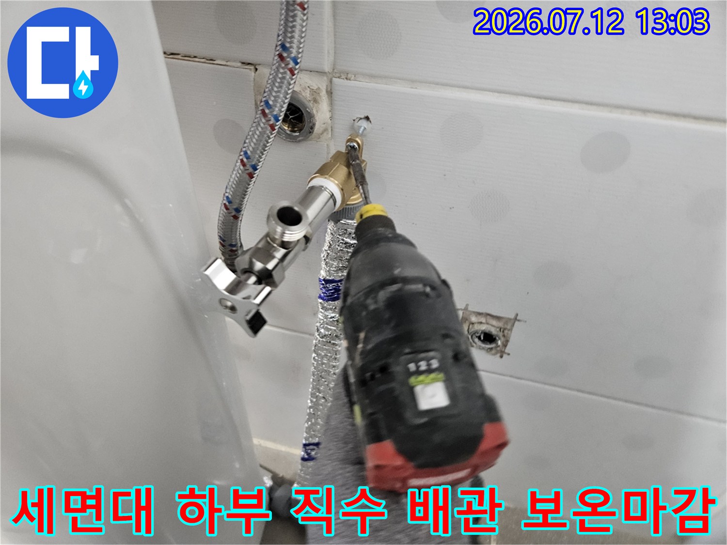 전동 드릴을 사용하여 세면대 연결용 노출형 직수 배관을 설치하는 모습
