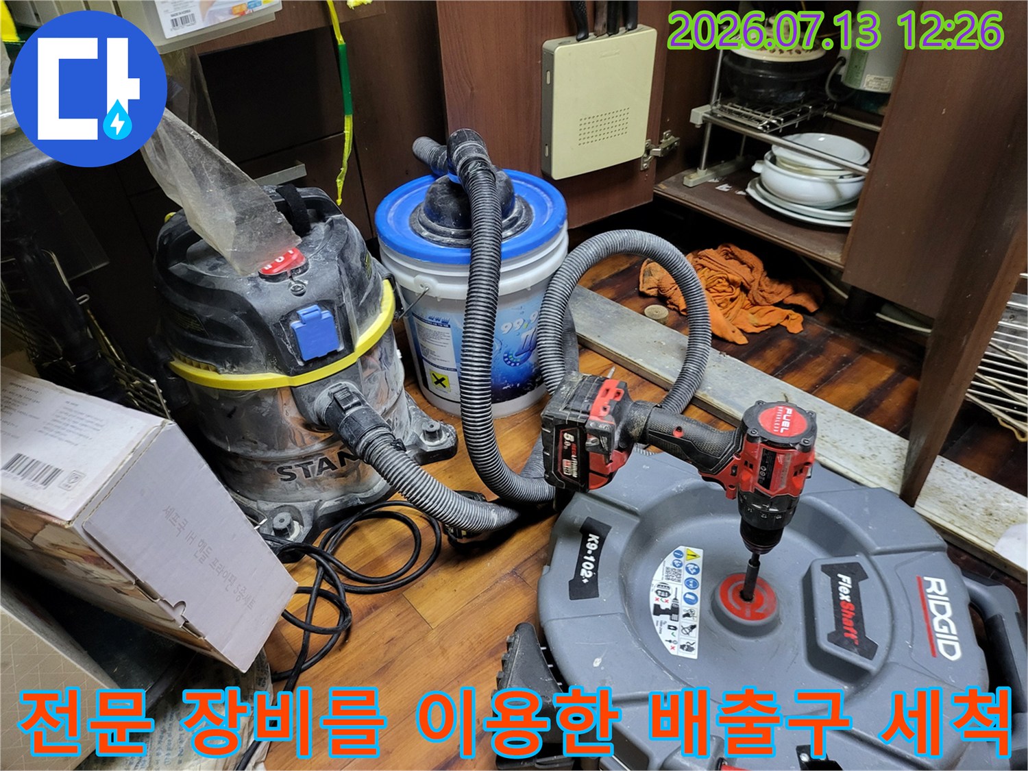 석션기와 내시경을 연결하여 싱크대 하부 배관을 청소하는 장면
