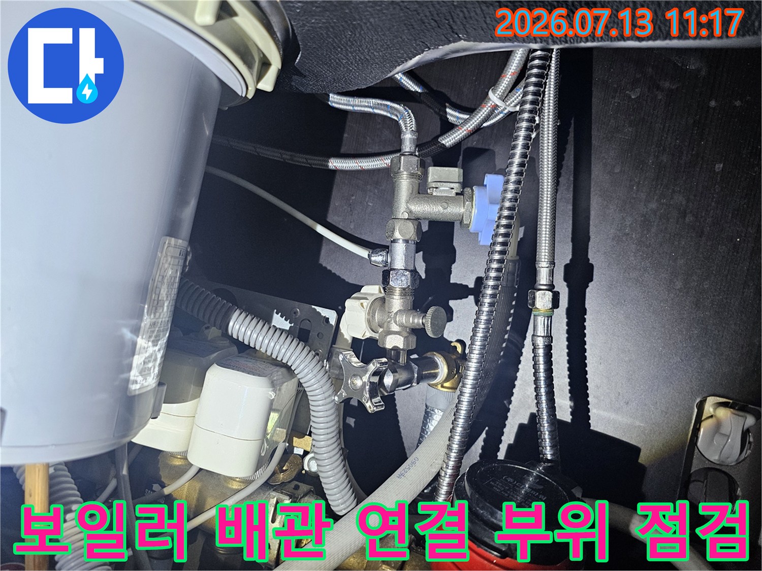 은색 금속 배관과 파란색 밸브가 복잡하게 연결된 보일러 하단-전경