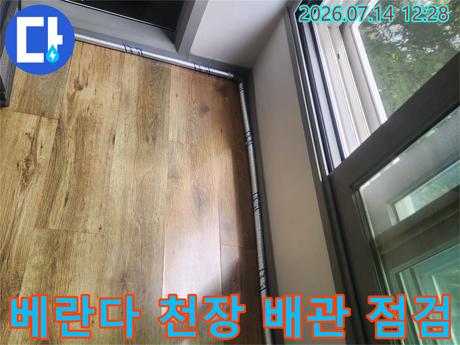 베란다 천장 아래 위치한 금속제 에어컨 드레인 호스와 목재 마감재의 상태 확인