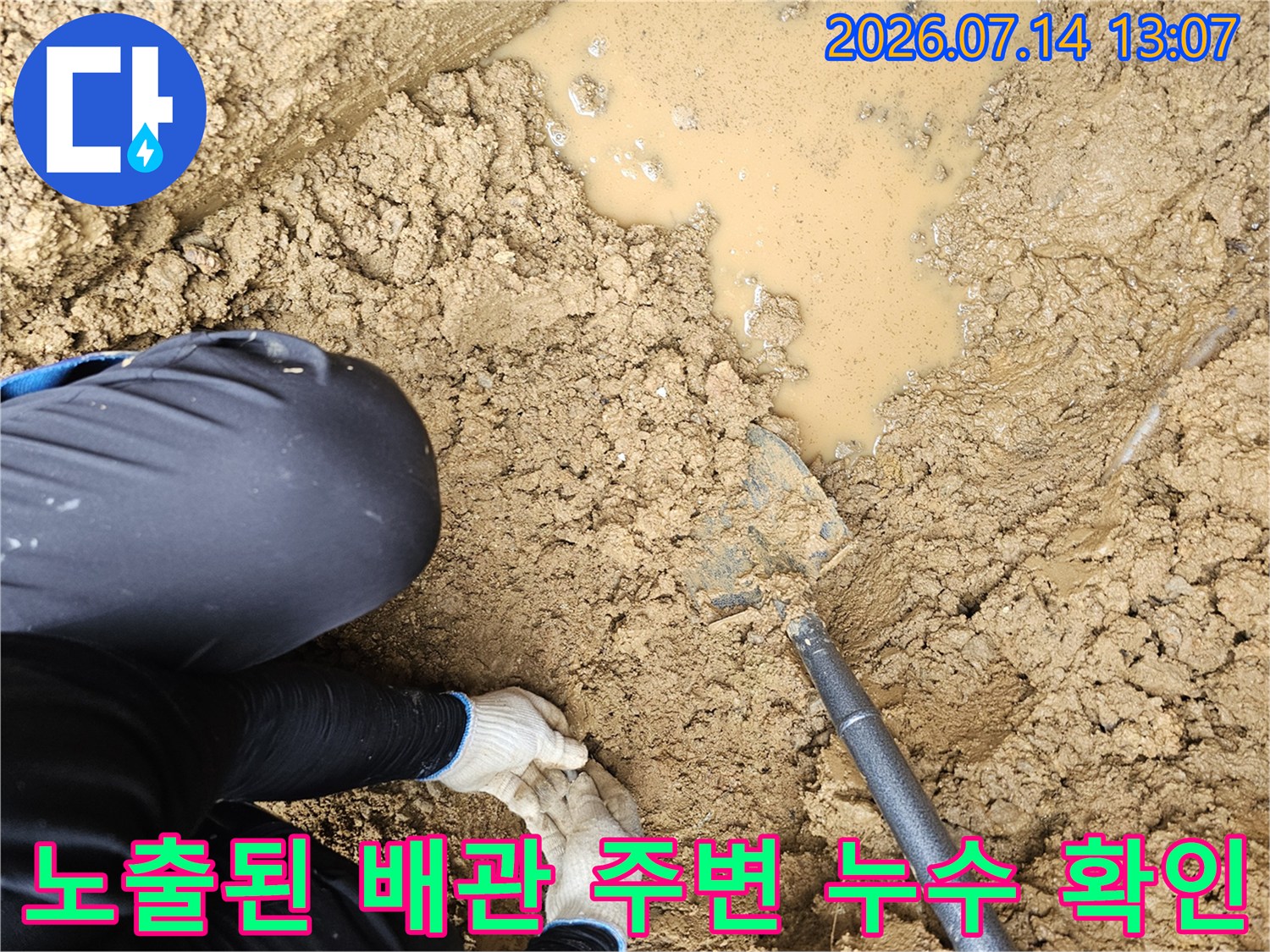 고인 물과 젖은 흙 사이로 드러난 배관 누수 지점의 모습