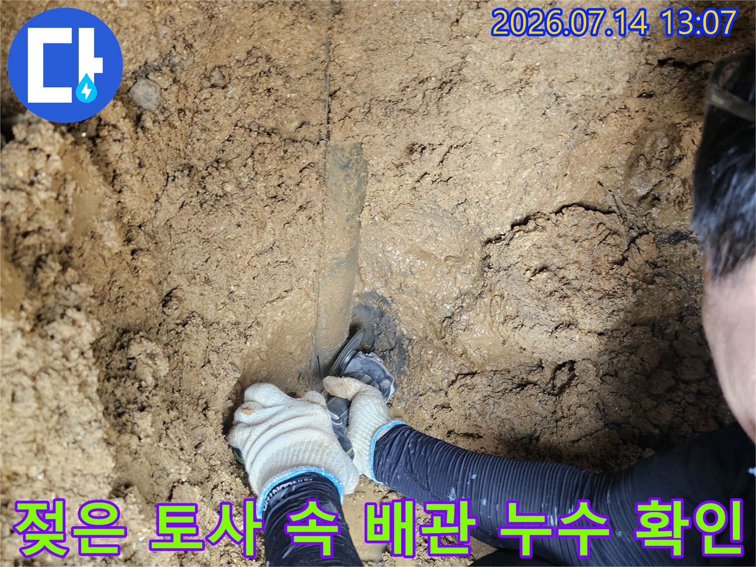 습한 흙 속에 파묻힌 노후된 상수도 배관을 점검하는 모습