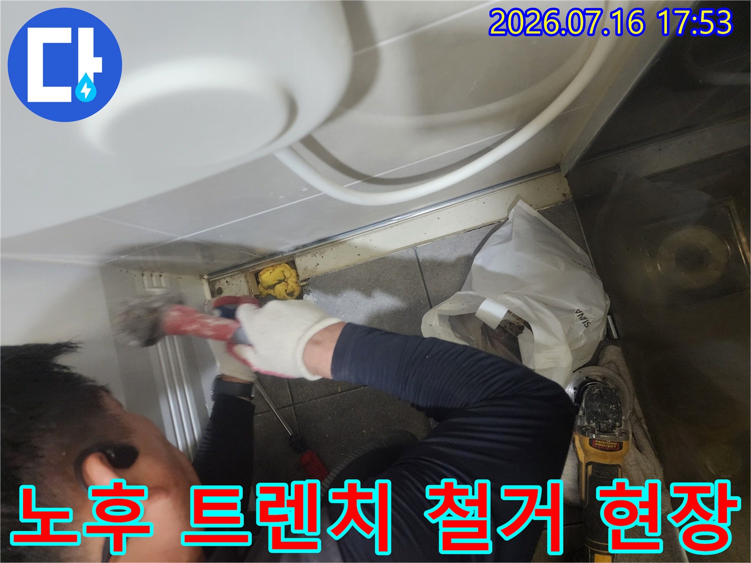 작업자가 전문 장비를 사용하여 화장실 바닥의 노후된 유가 구조물을 제거하는 모습