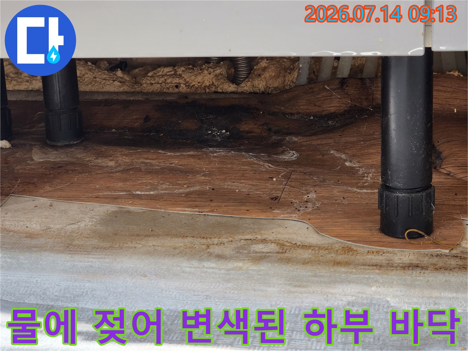 싱크대 지지대 근처의 나무 판넬이 누수로 인해 검게 물든-장면