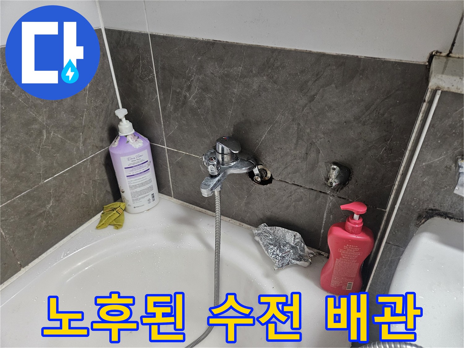욕조 하단 벽면의 노출된 수도 배관과 타일 파손 부위