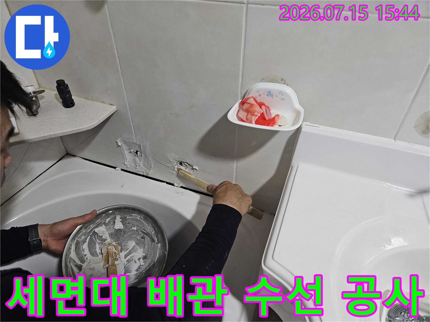 노출된 세면대 하부 배관을 손으로 직접 점검하며 보수하는 장면