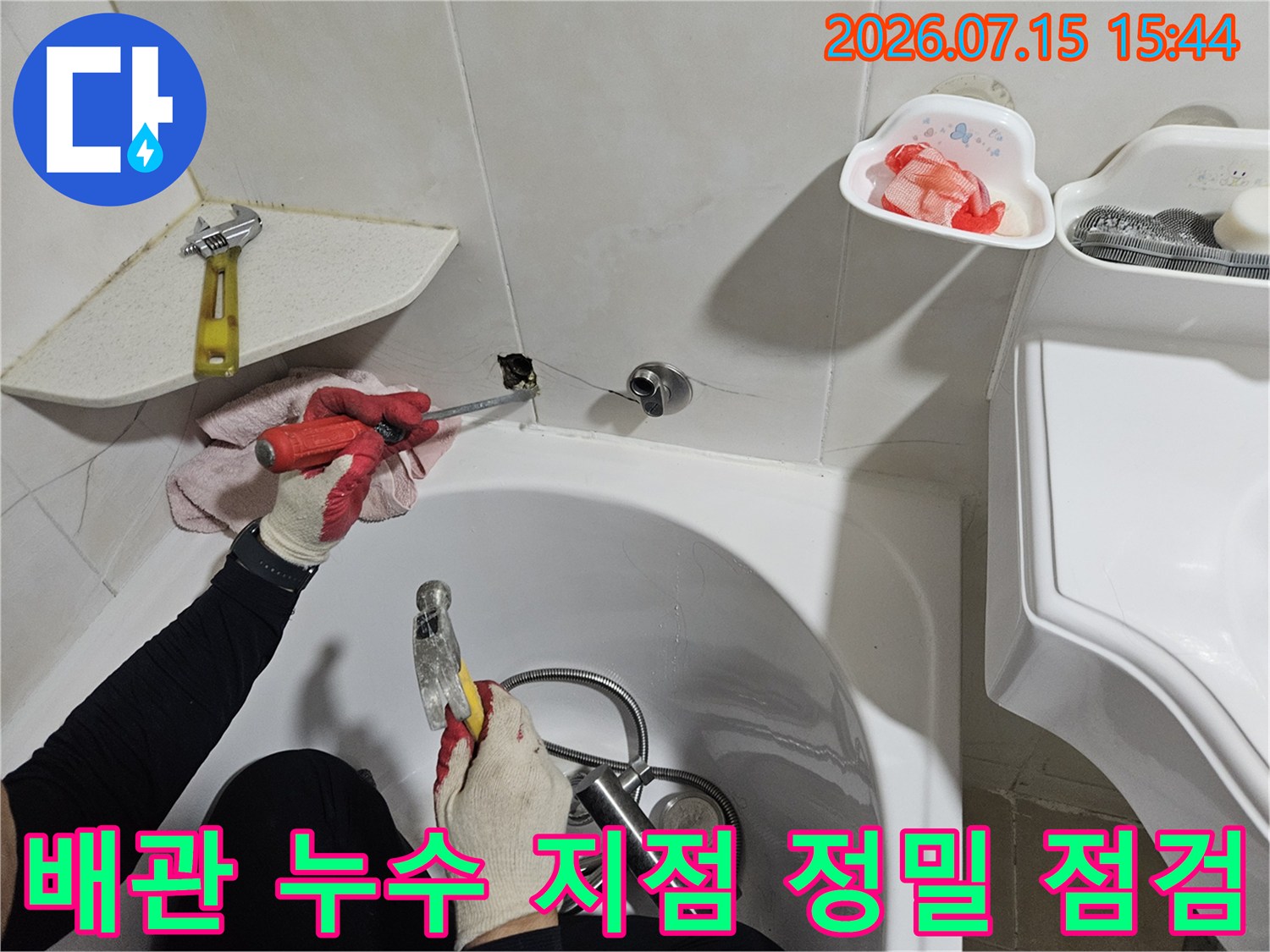 세면대 밑 배관을 수리하기 위해 장비와 도구를 사용하여 세부적으로 확인하는 작업자