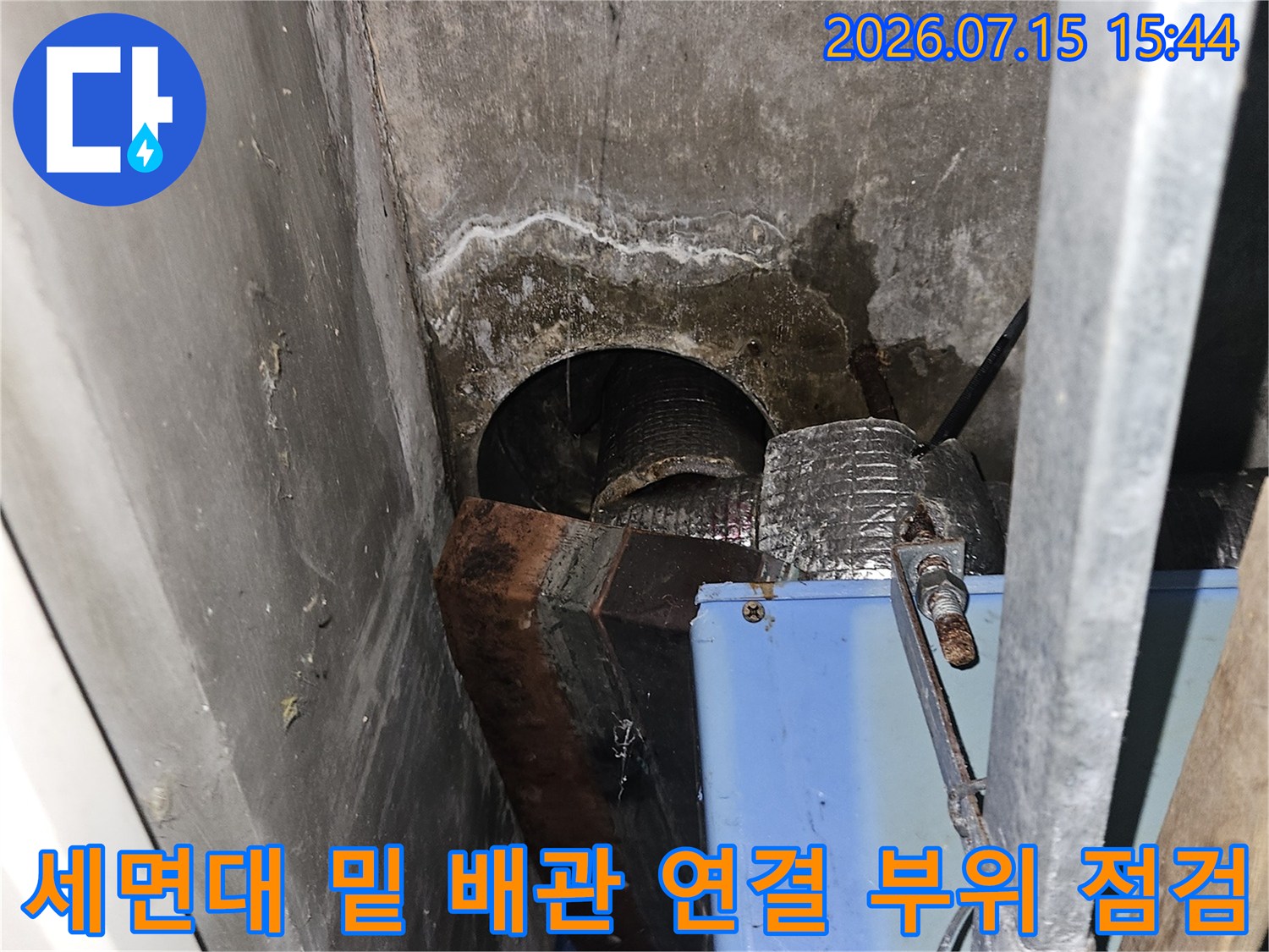 세면대 하부 구조물 사이로 노출된 배관의 누수 지점 확인 장면