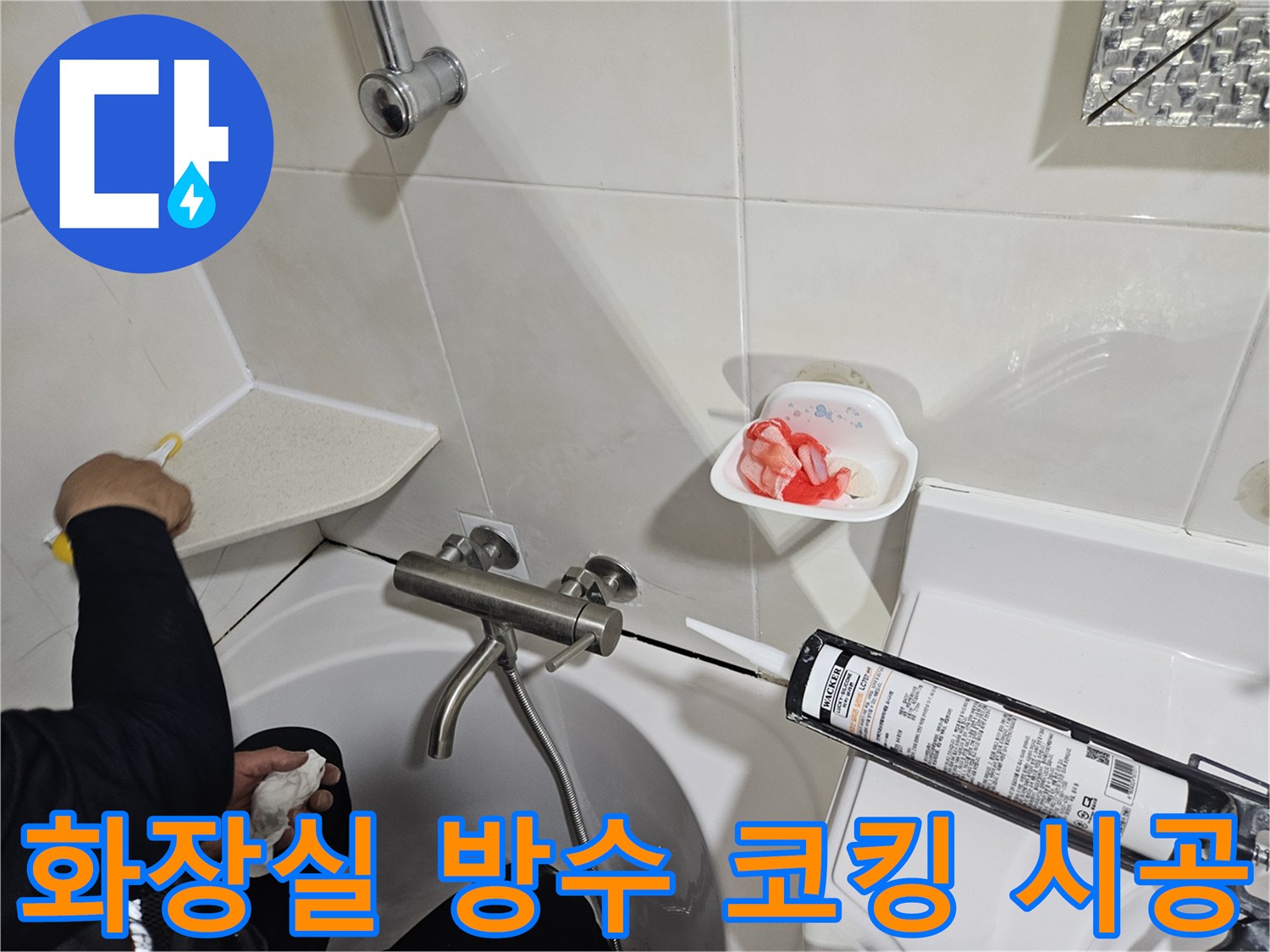 실리콘 건을 사용하여 욕조 경계면에 마감재를 채우는 장면입니다.