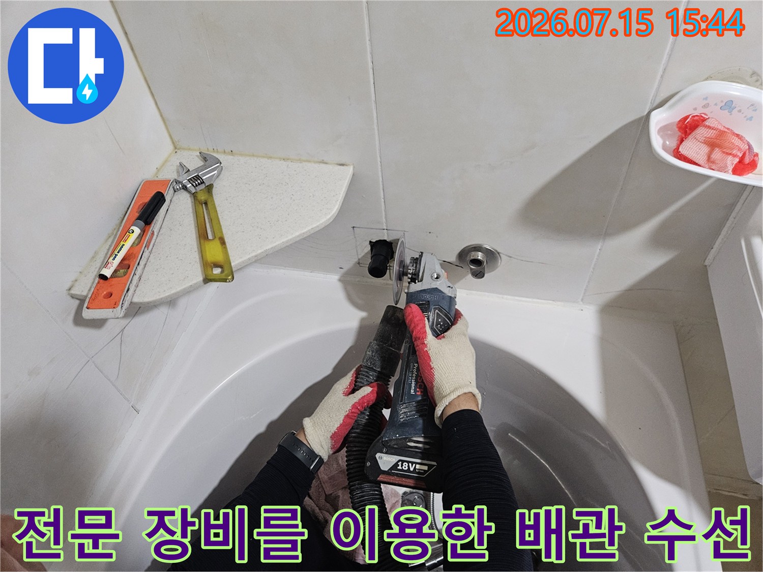 장갑을 낀 작업자가 세면대 아래 누수 부위를 집중적으로 보수하는 모습