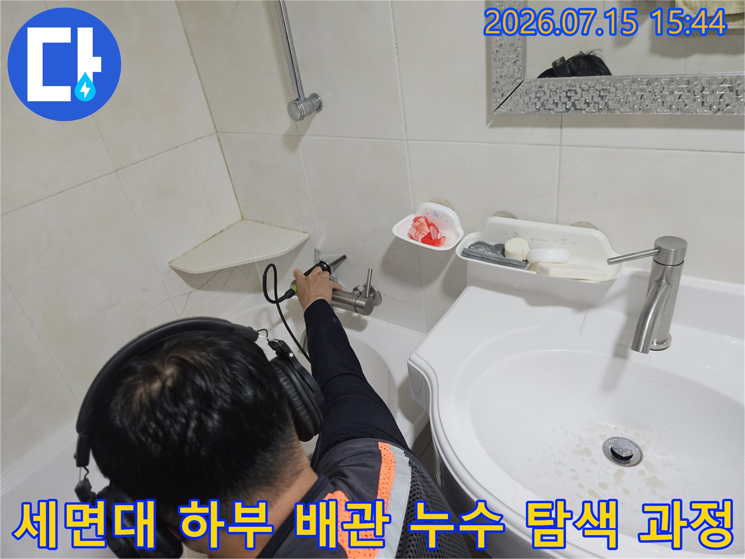 청음 장비를 사용하여 세면대 아래쪽 배관의 이상 여부를 정밀하게 점검하는 모습