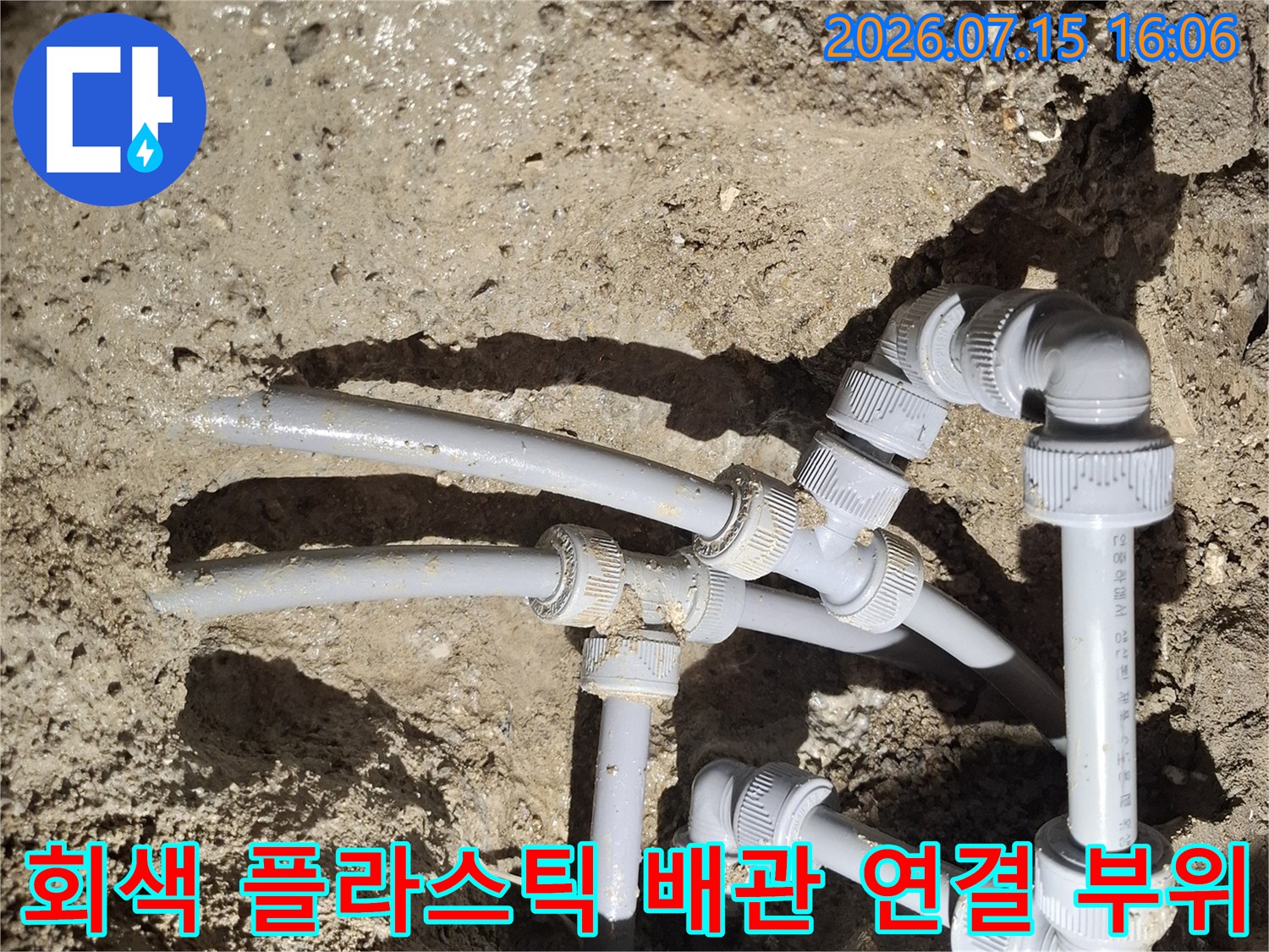 흙바닥 아래에 매립된 회색의 수도 배관과 엘보우 부속들이 복잡하게 연결되어 있는 모습