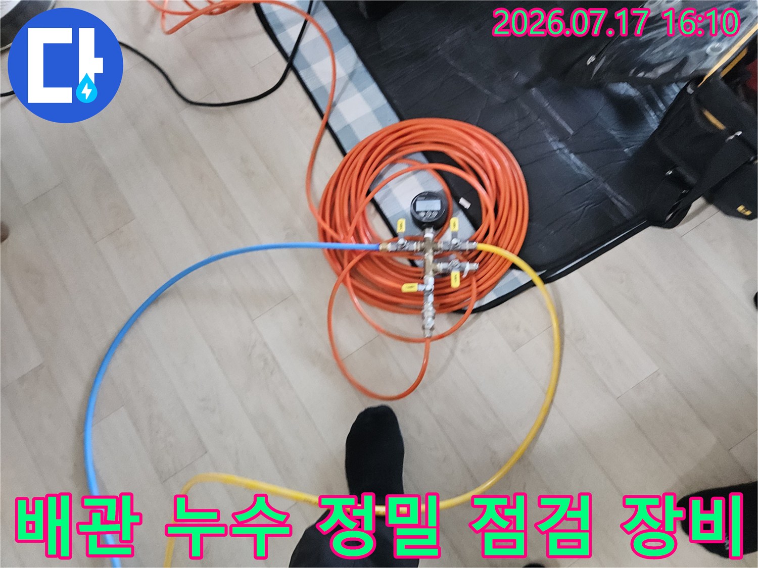 오렌지색 호스들과 게이지가 연결된 화장실 배관 공압 측정기구