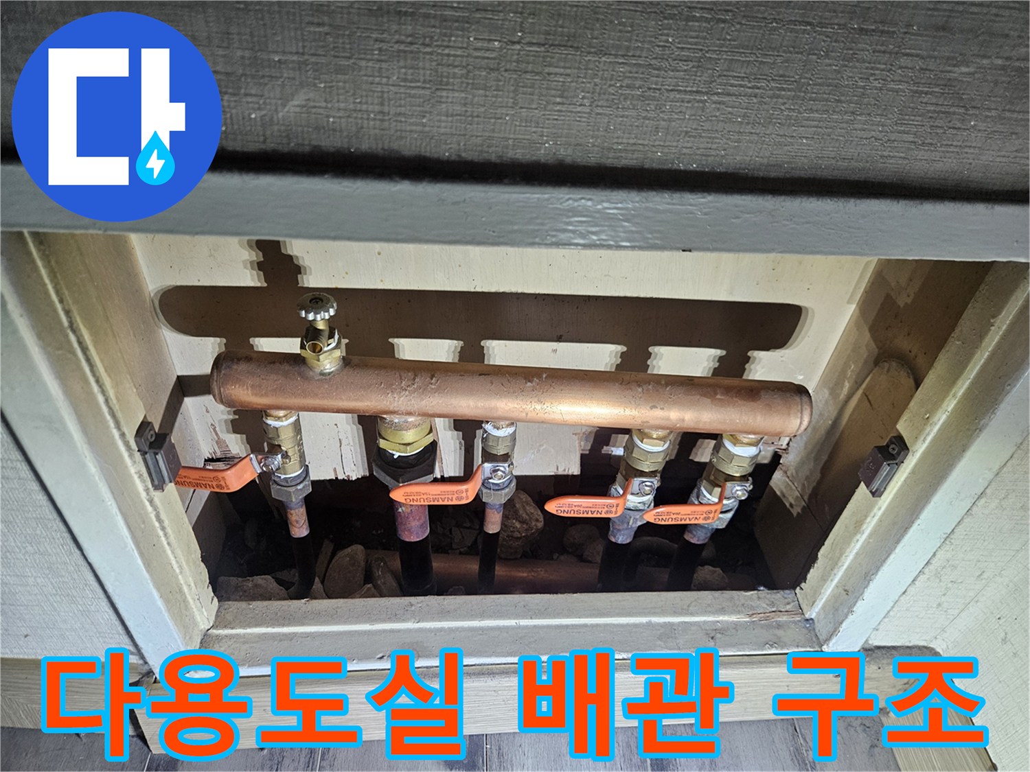다용도실 벽면 안쪽의 구리 관과 주황색 레버 밸브가 노출된 모습