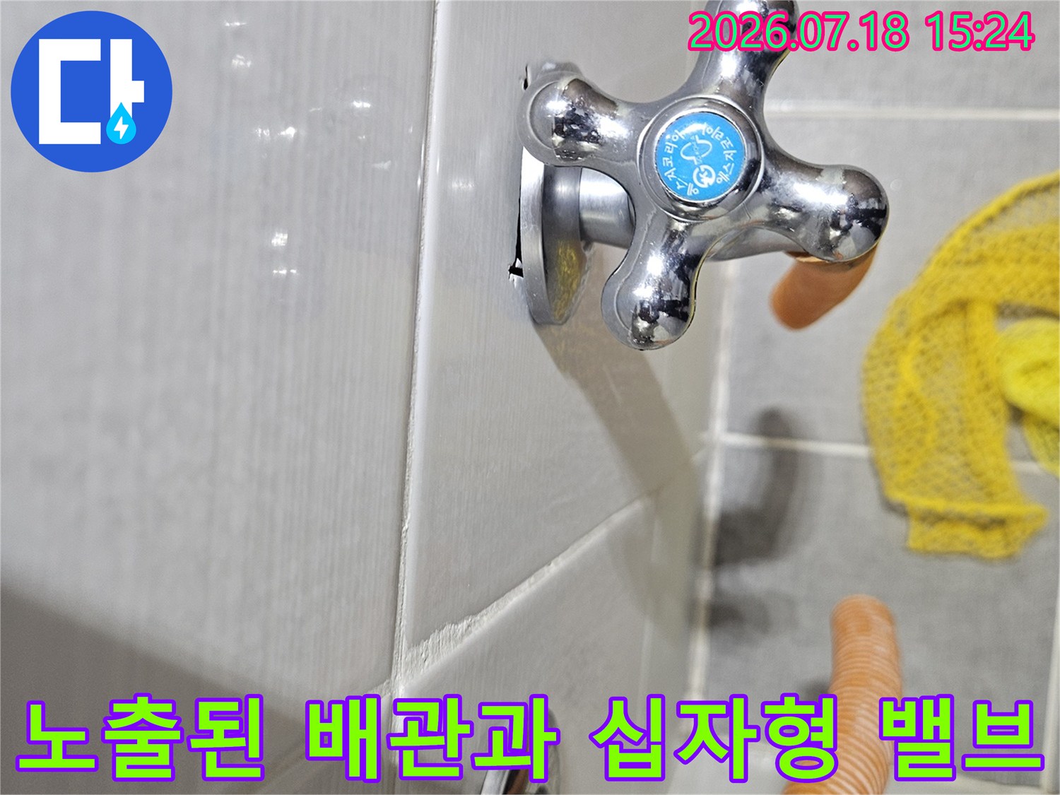 흰색 타일 위 설치된 크롬 도금 수도 밸브와 오렌지색 보호재