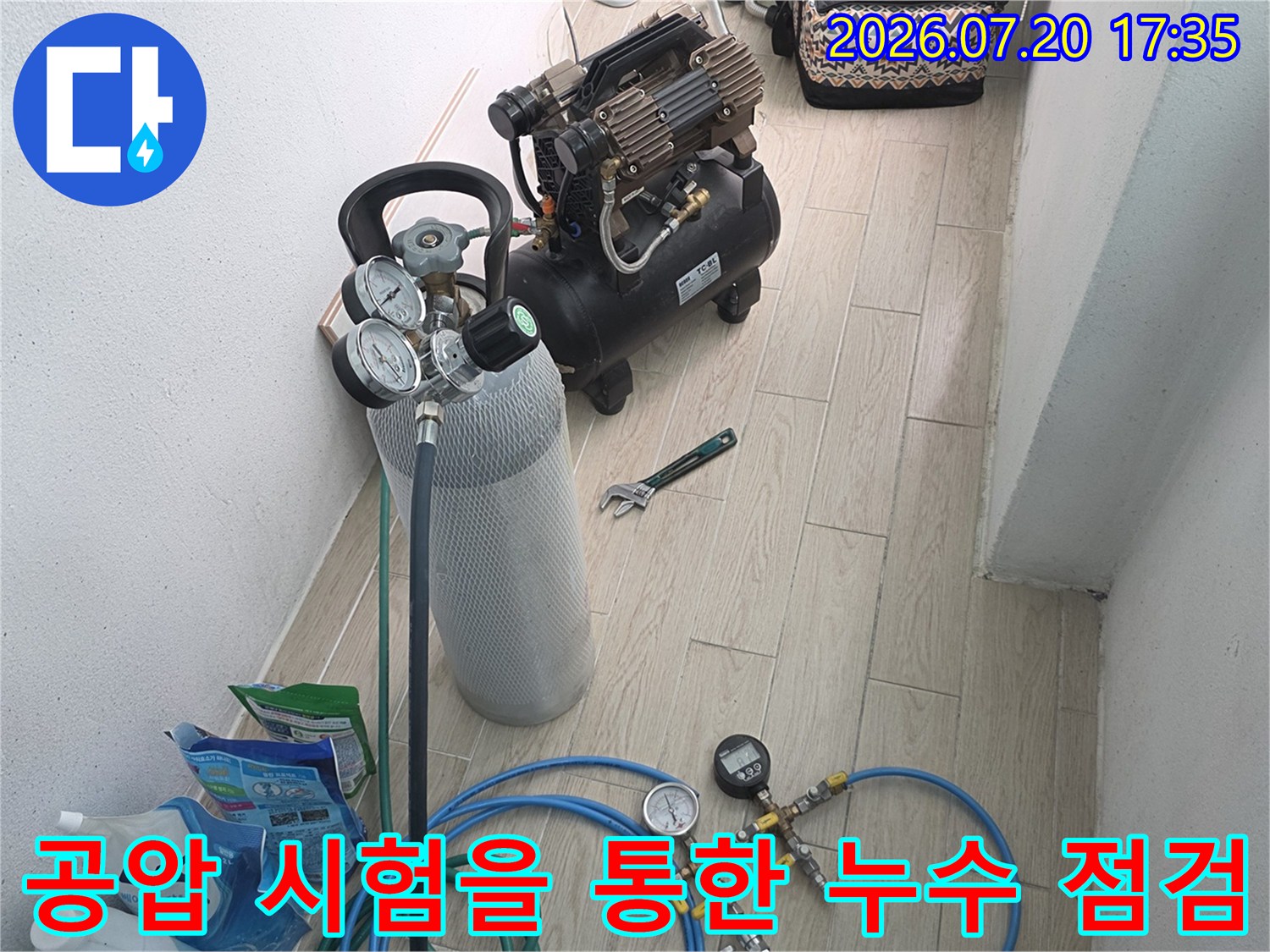 압력 게이지와 파란색 호스가 연결된 장비로 보일러 배관의 기밀성을 테스트하는 장면