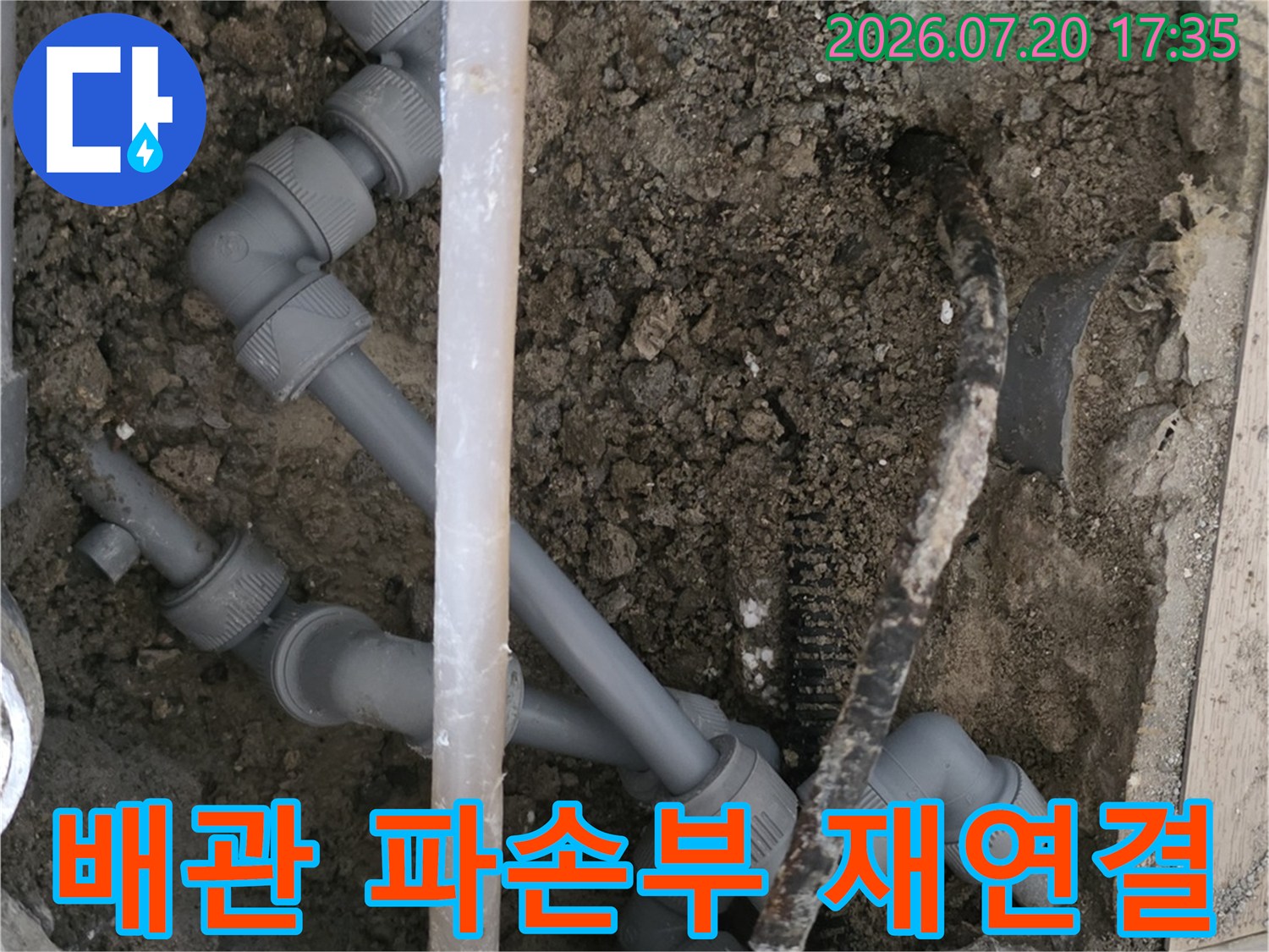 어질러진 흙 속에서 노출된 배관을 새 부속으로 교체하는 장면