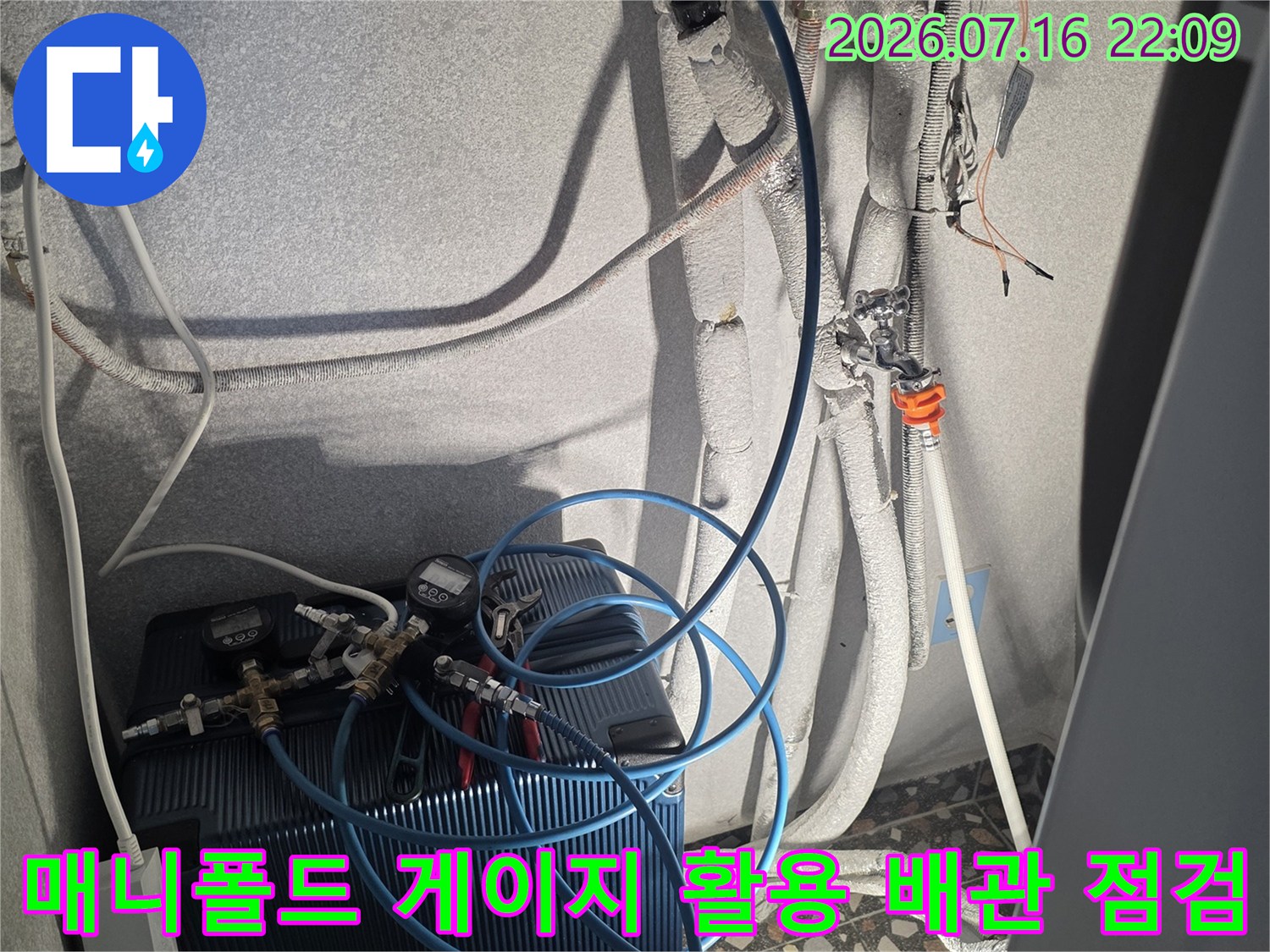 에어컨 실외기 연결부에서 매니폴드 게이지를 사용하여 시스템의 이상 유무를 정밀 진단하는 장면입니다.