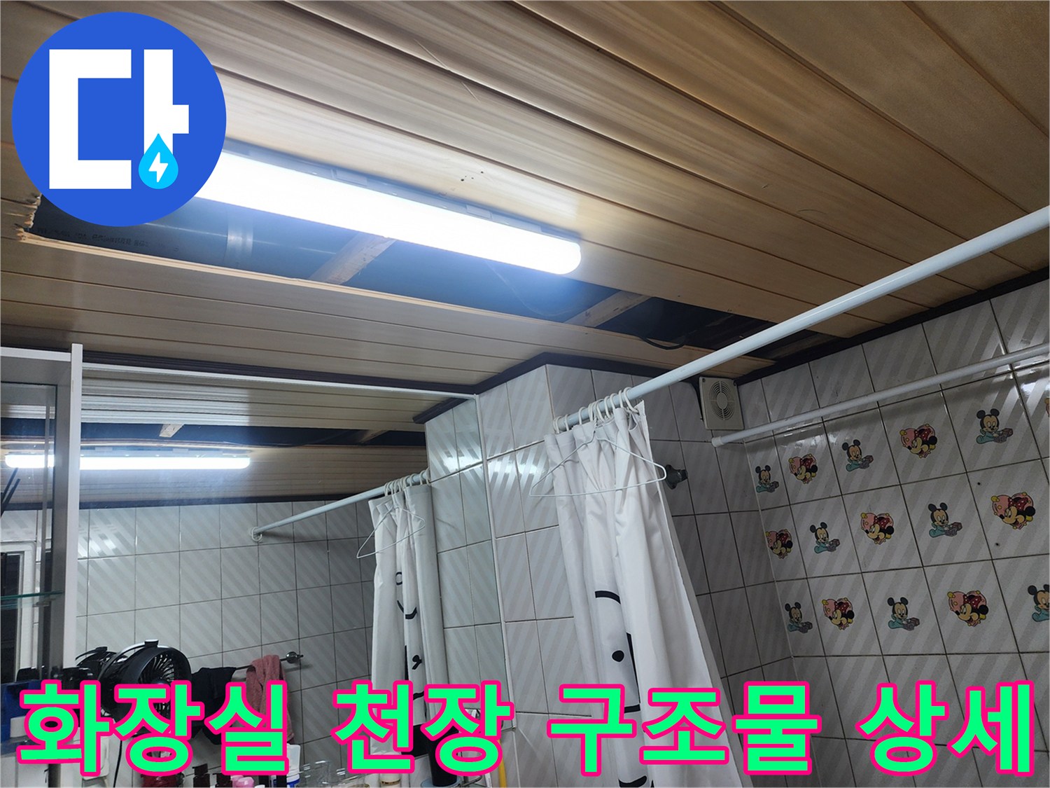조명이 설치된 화장실 천장과 타일 벽면 사진
