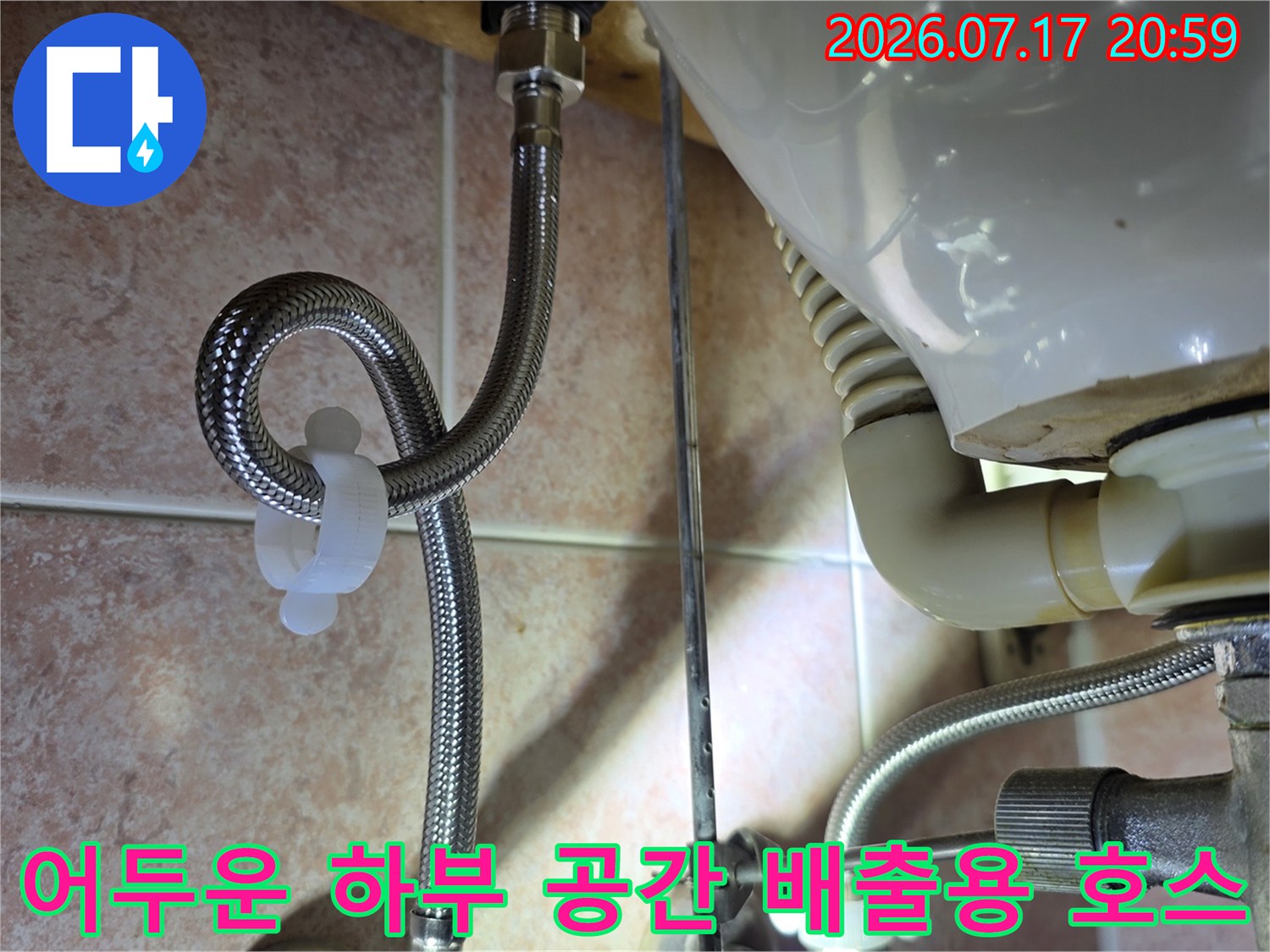 싱크대 밑 어두운 구역에 위치한 배출용 호스의 연결 상태를 점검하는 모습