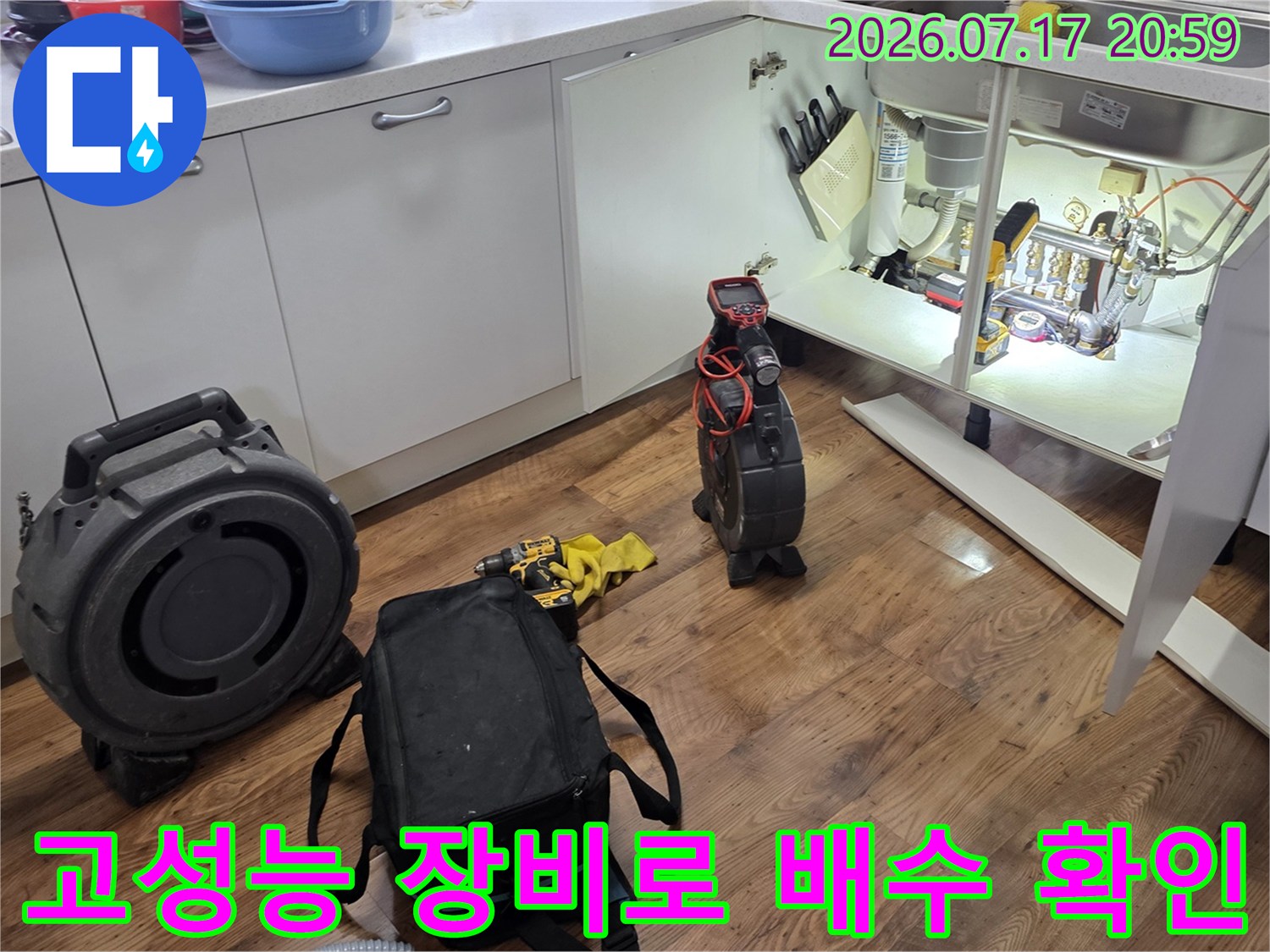싱크대 아래에 가스 탐지기와 청음기 등 전문 장비를 배치하여 배관 누수를 점검하는 모습