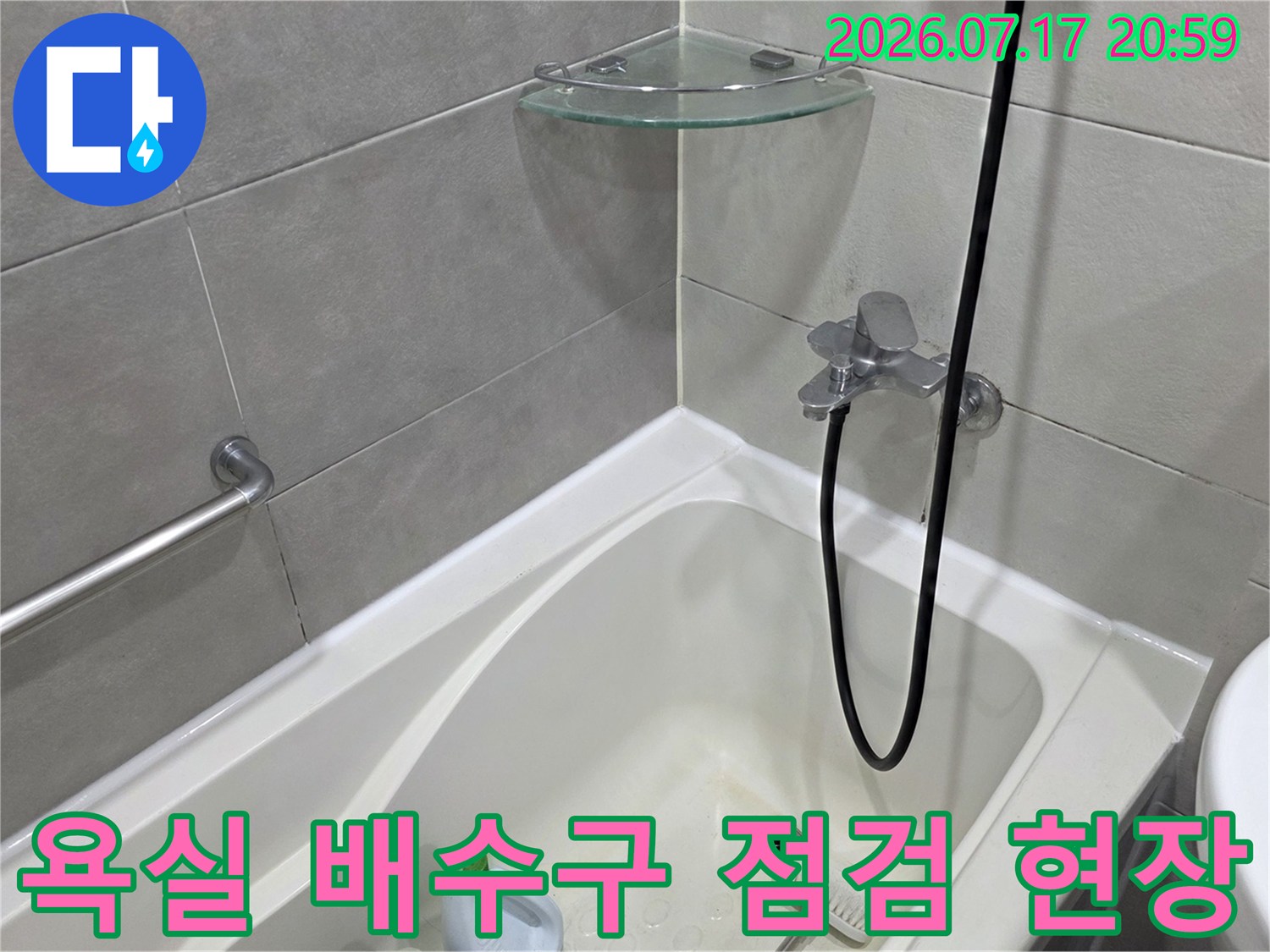 욕실 바닥에 위치한 배수구 주변의 노출된 배관과 샤워기 수전 부위