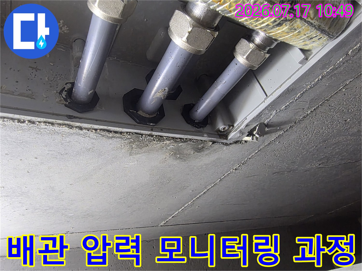 압력 게이지와 호스로 구성된 장비를 배관에 연결해 기밀성을 검사하는 장면