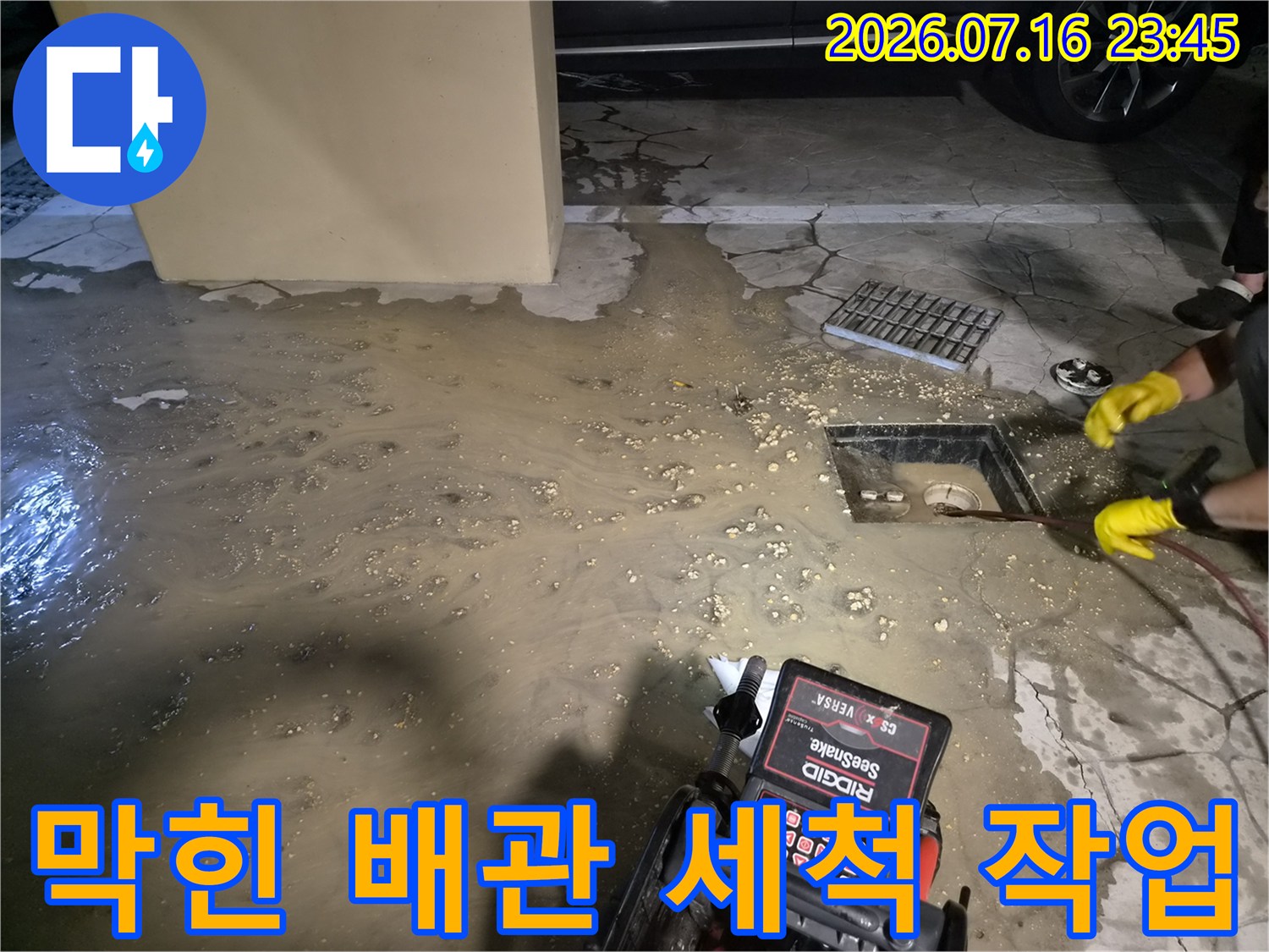 배관 세척 장비와 막힌 배수구 주변의 오염된 바닥 현장