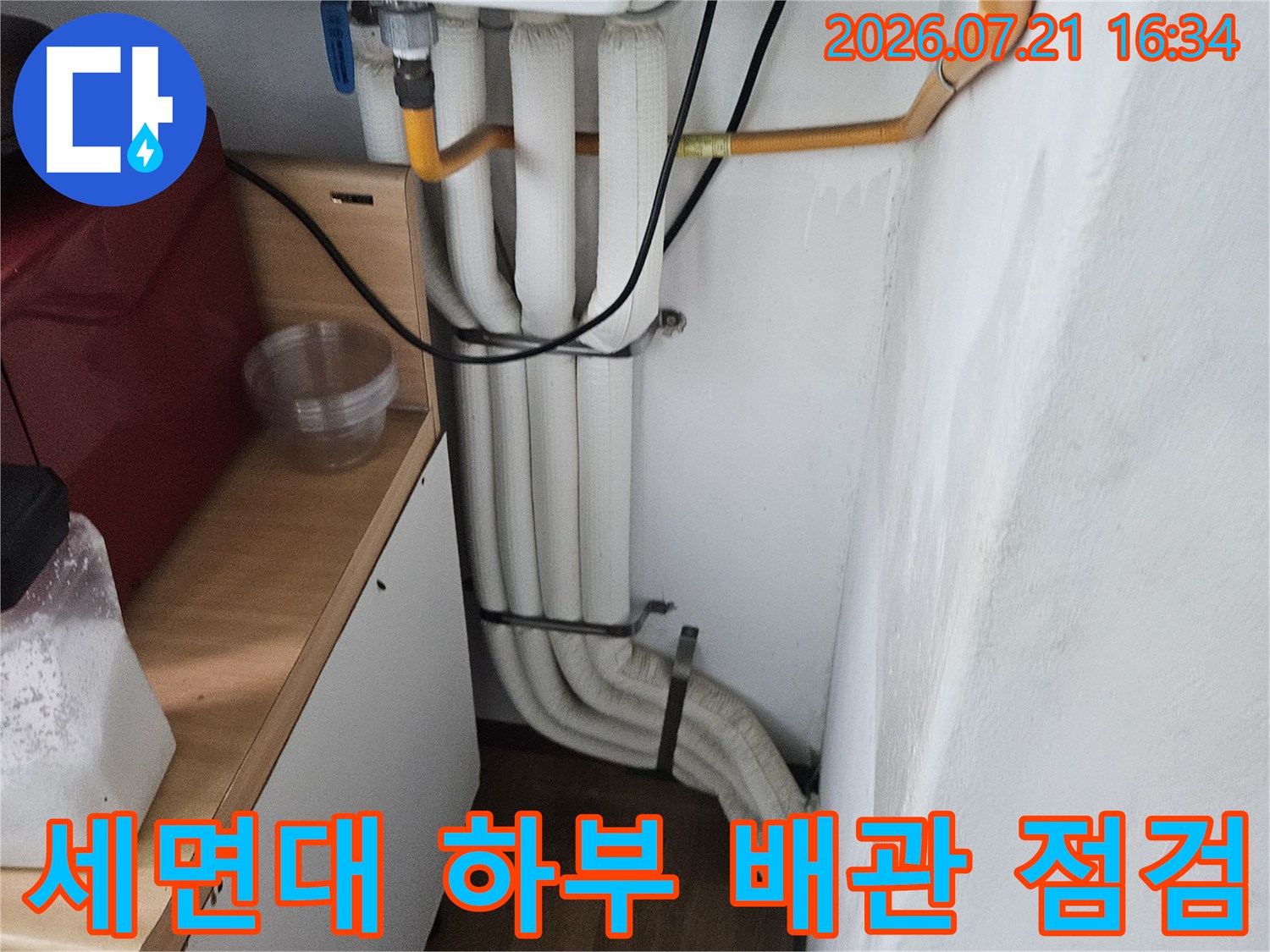 세면대 아래쪽으로 노출된 여러 개의 흰색 및 노란색 배관과 연결 부위 점검