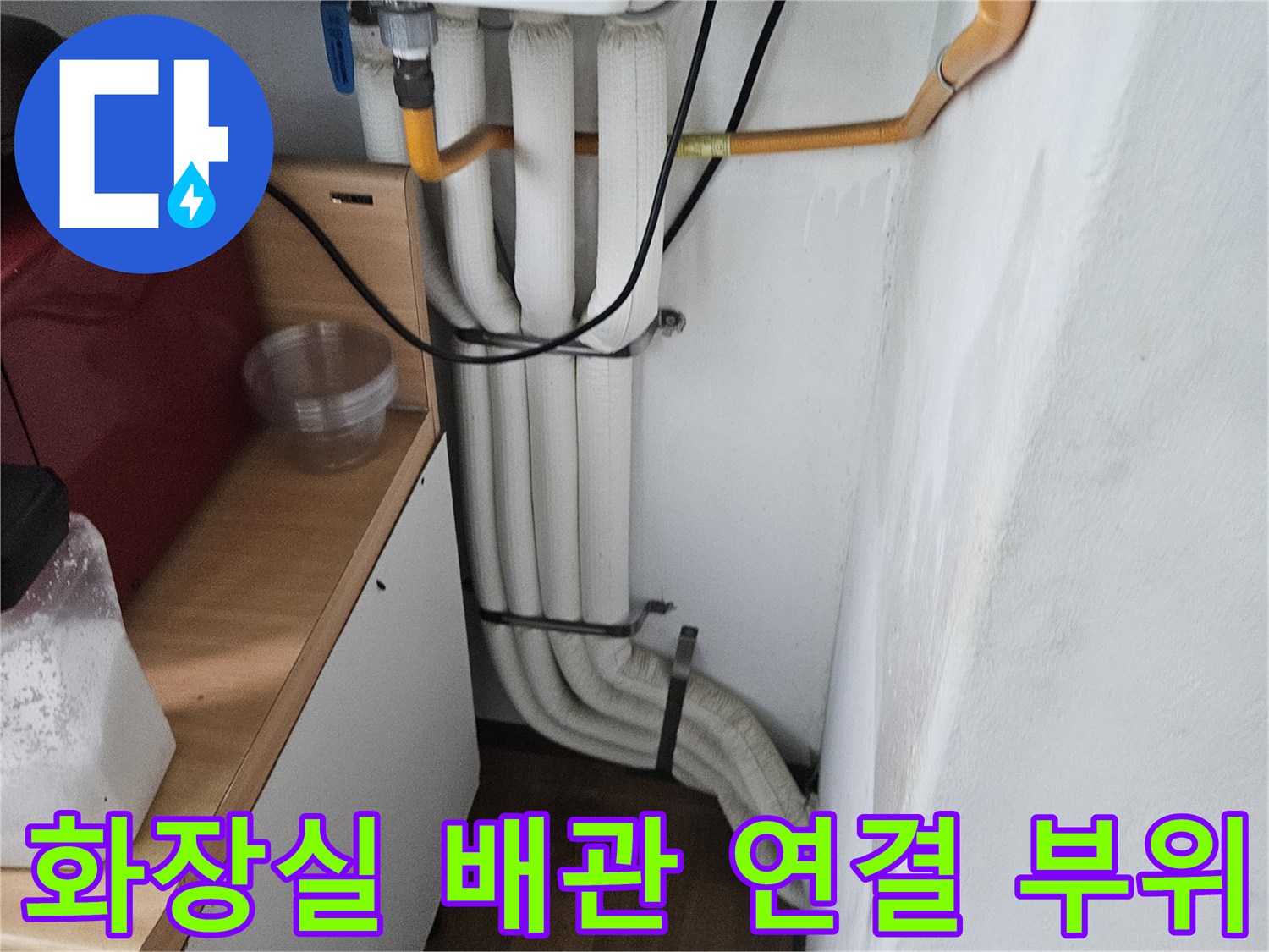 흰색 배관과 노란색 배관이 겹쳐진 세면대 하부 모습