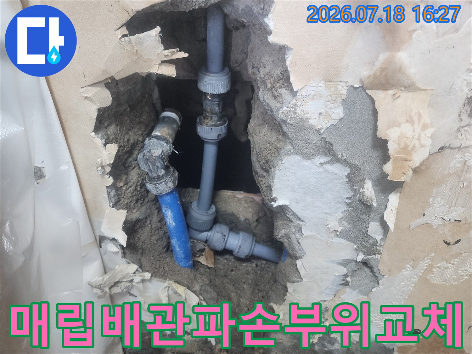 벽 내부에서 발견된 파란색 수도 배관의 연결 부속 교체 장면-주변 콘크리트 잔해물