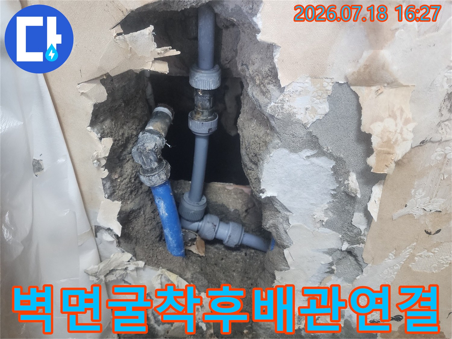 회색 콘크리트 벽체 속에 설치된 파란색 수도관-엘보우 부속 연결 부위