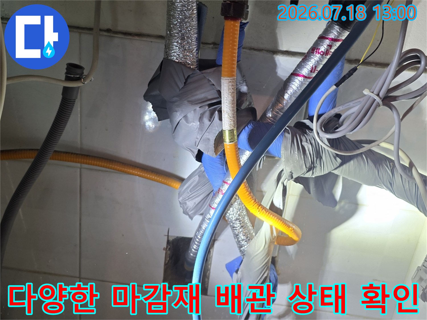 노란색 보호관과 은색 단열재 및 파란색 호스가 복합적으로 연결된 수도 배관 구조