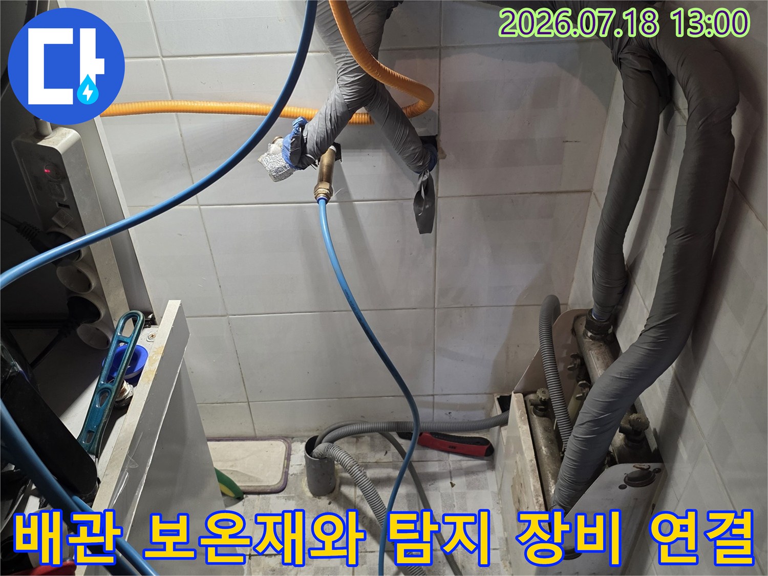 회색 보온재가 감싸진 상단 배관과 하단에 연결된 파란색 압력 검사 호스-누수 진단 장면