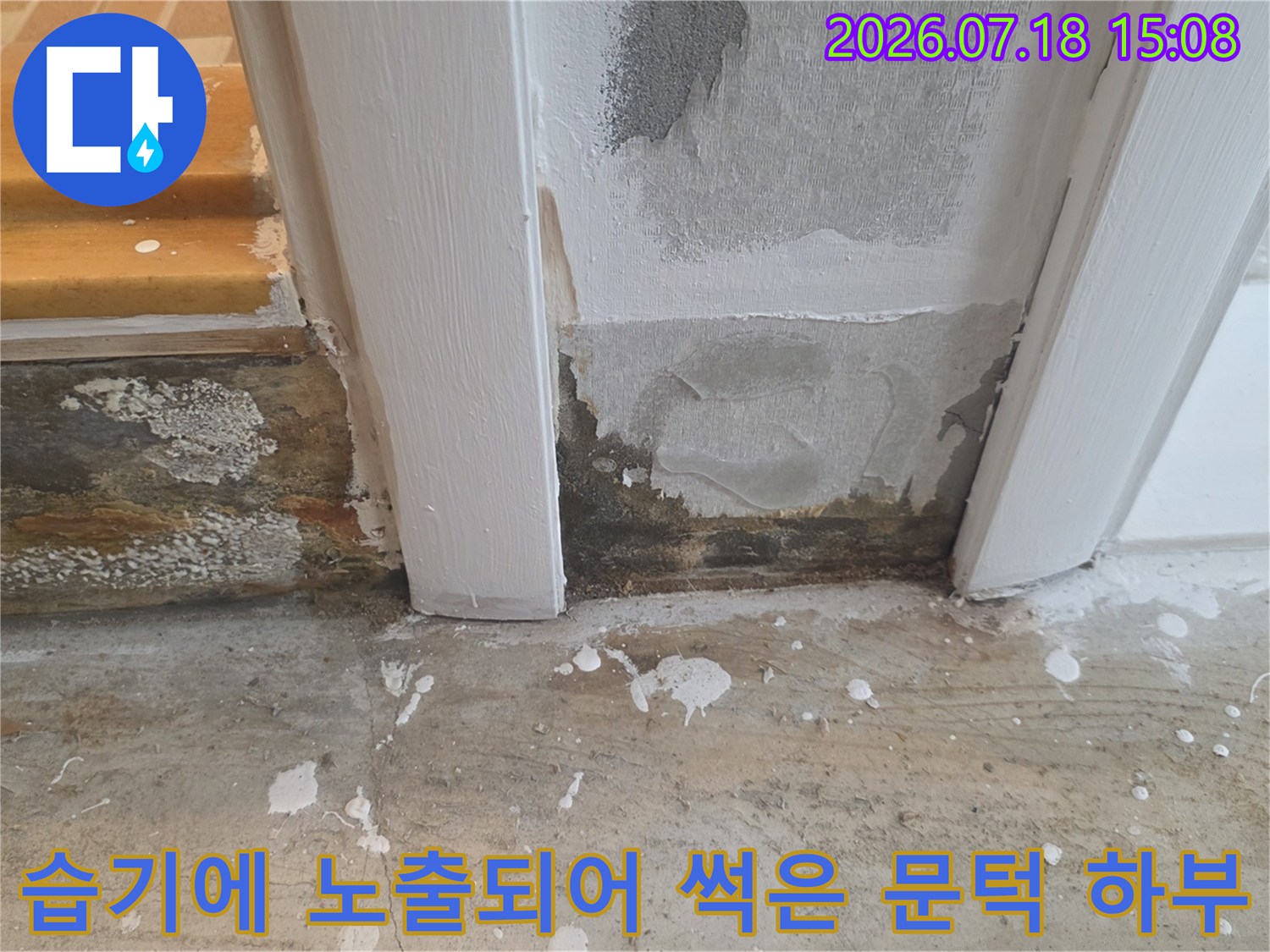 흰색 욕실 문틀 아래쪽 시멘트와 마감재가 검게 변색되고 부식된 사진