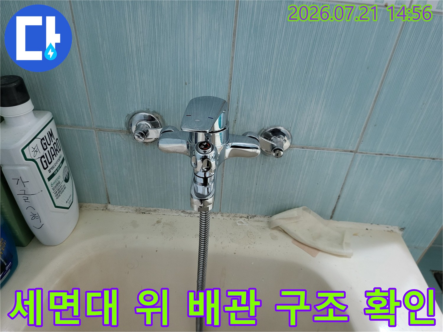 욕실 세면대에 설치된 크롬 수전과 주변의 배관부 구성 촬영