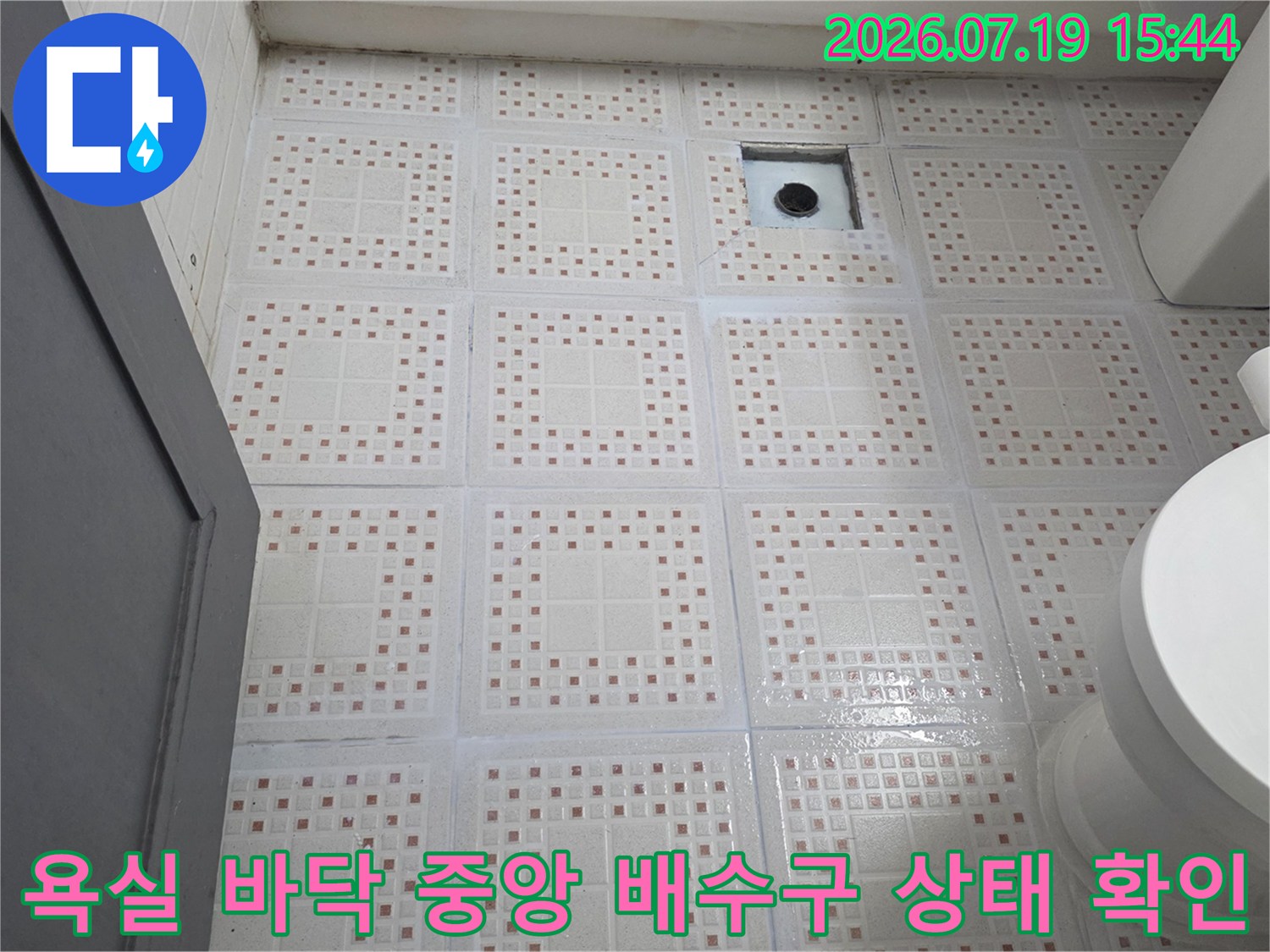 격자 무늬가 들어간 흰색 욕실 타일과 금속 재질의 하수구 유가 모습