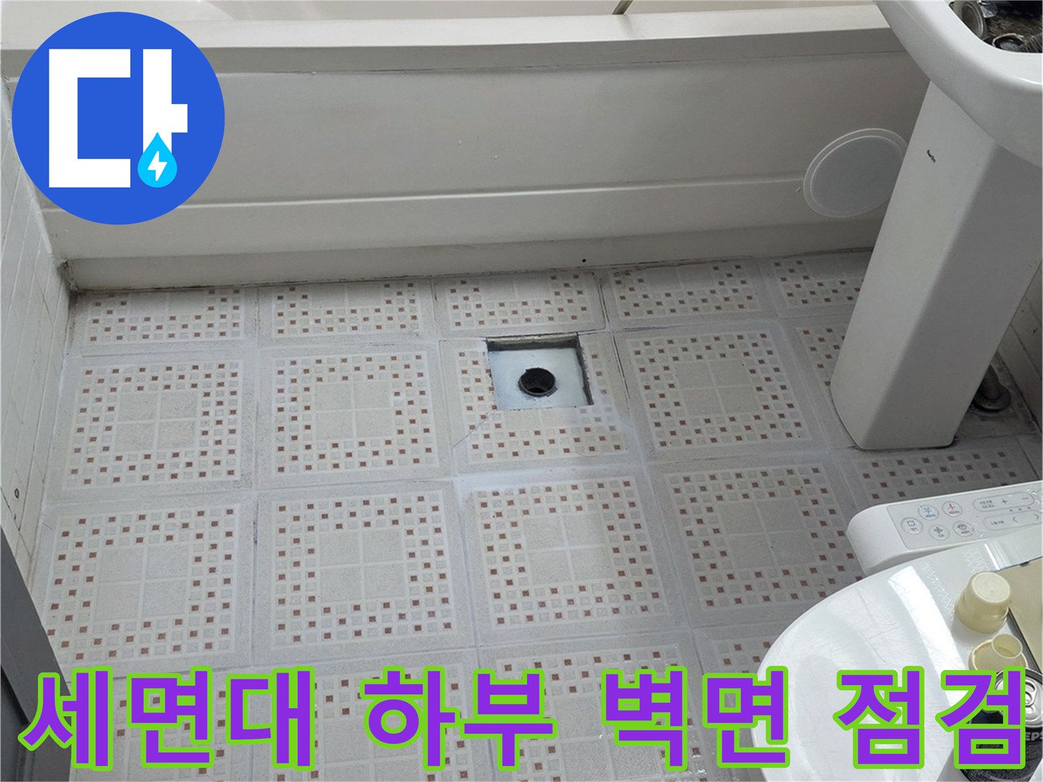 세면대 아래쪽의 패턴 타일과 배관 연결 부위를 보여줍니다.