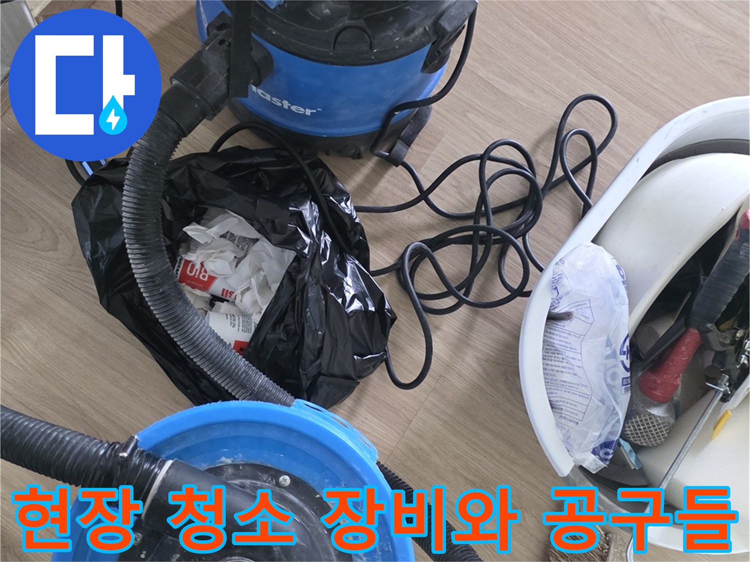 작업 현장에 놓여 있는 대형 진공 청소기와 작업 도구 바구니