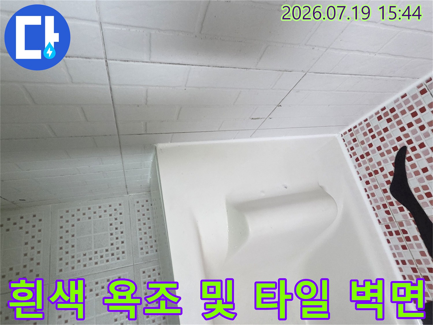 흰색 욕조-우측의 작은 붉은색 계열 타일벽과 천장재가 보이는 내부 사진