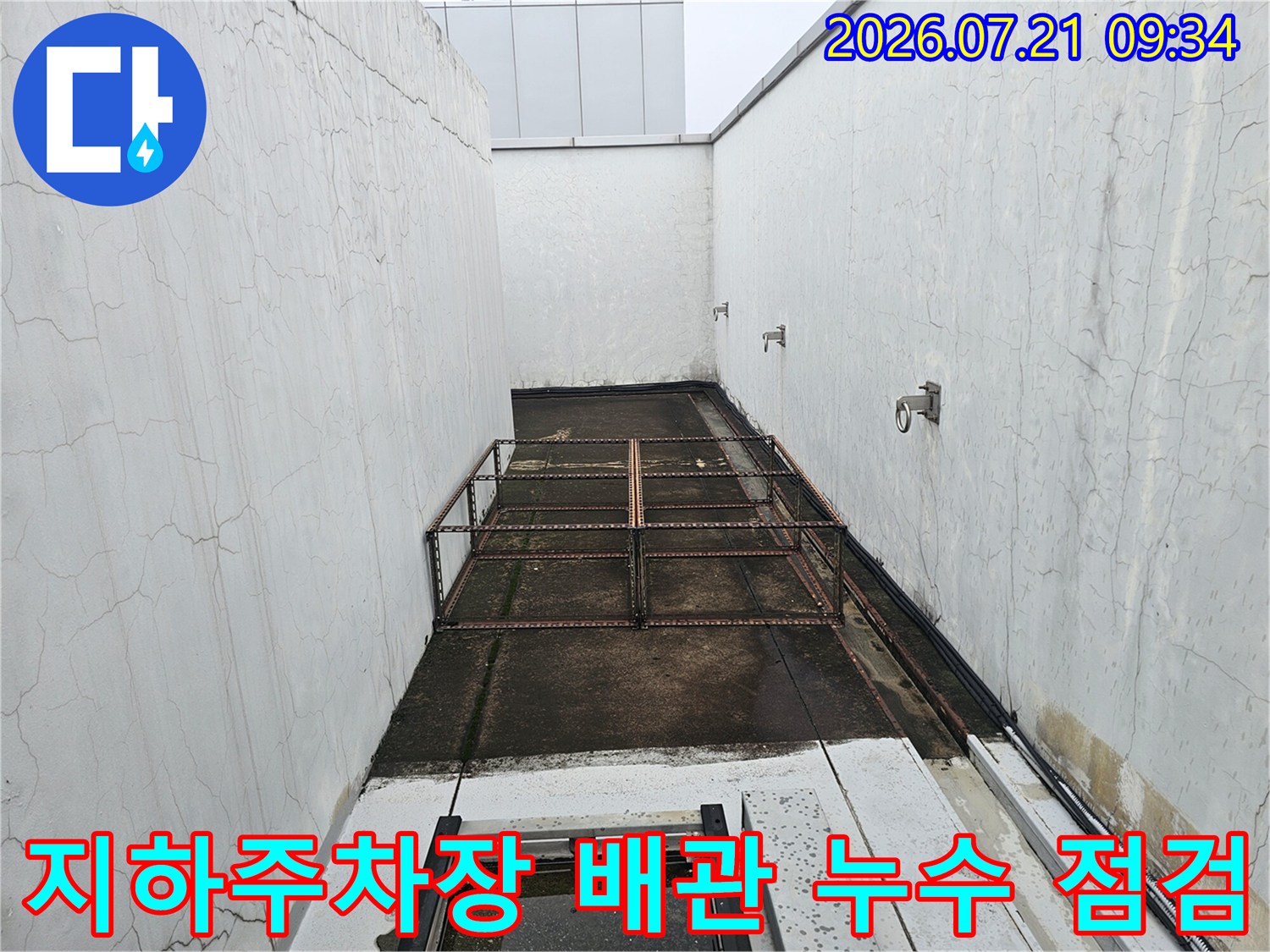 흰색 벽면과 금속 배관이 노출된 지하 주차장 배관 점검 현장