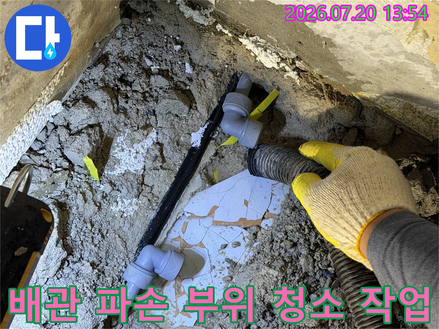 노란색-작업-장갑을-낀-엔지니어가-파손된-배관-주변을-청소기로-흡입하는-장면