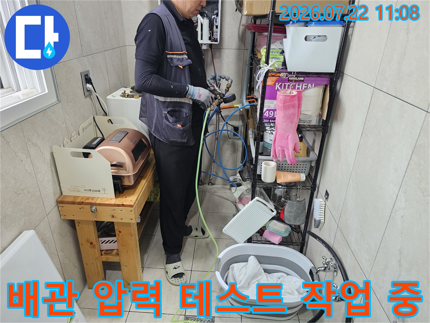 작업복을 입은 전문가가 배관 연결 부위에 측정 장비를 설치하고 점검하는 장면