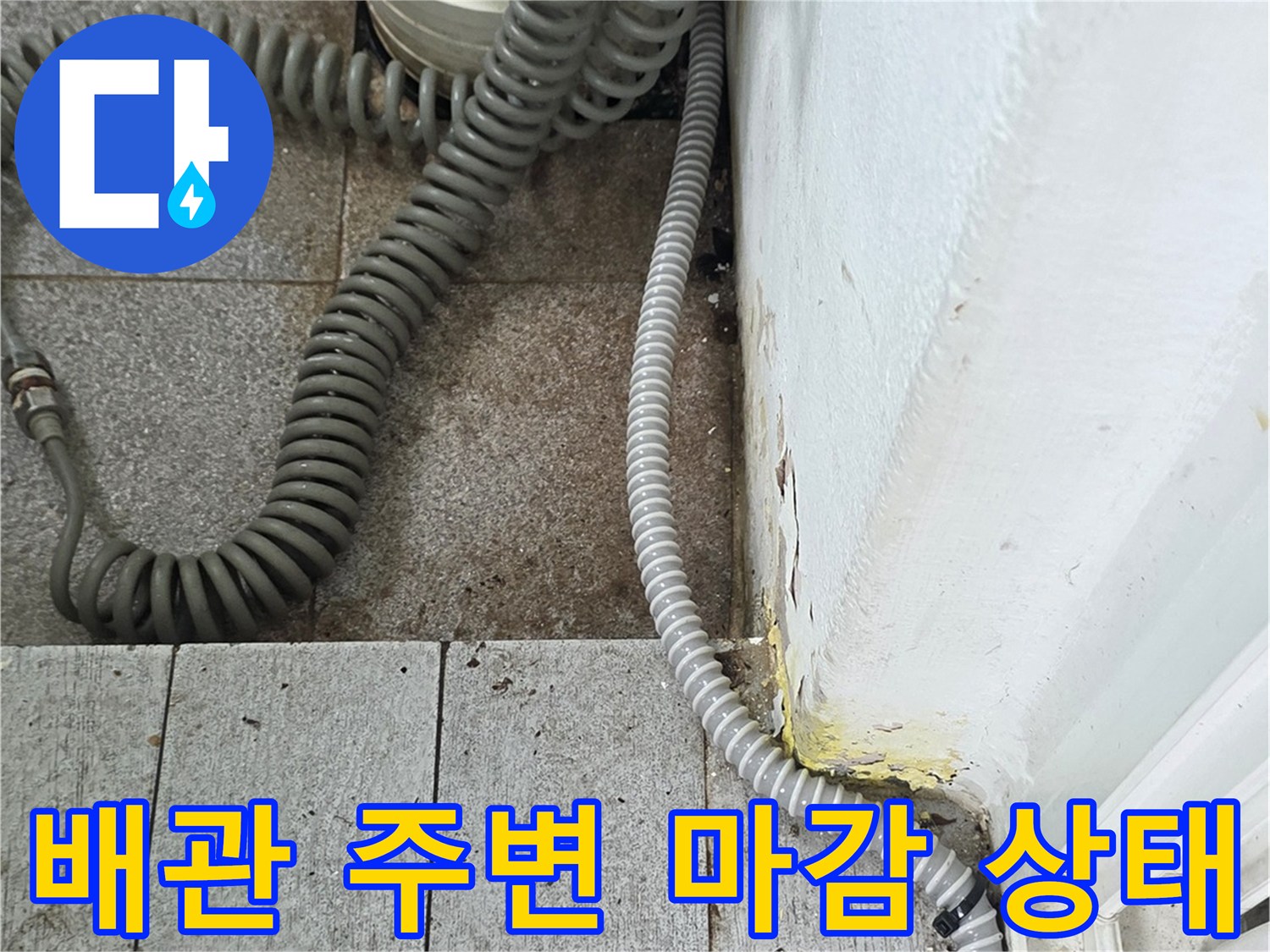 회색 주름 호스와 하얀색 수직 관이 연결된 배관 구조입니다.