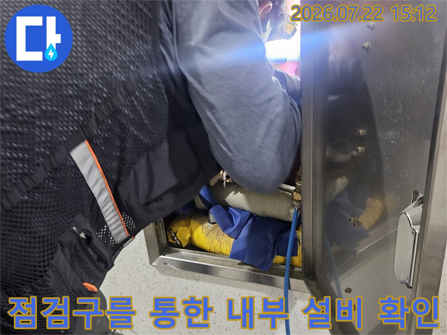 금속 덮개가 열린 천장 점검구 안으로 손과 머리를 넣어 배관을 살피는 작업자
