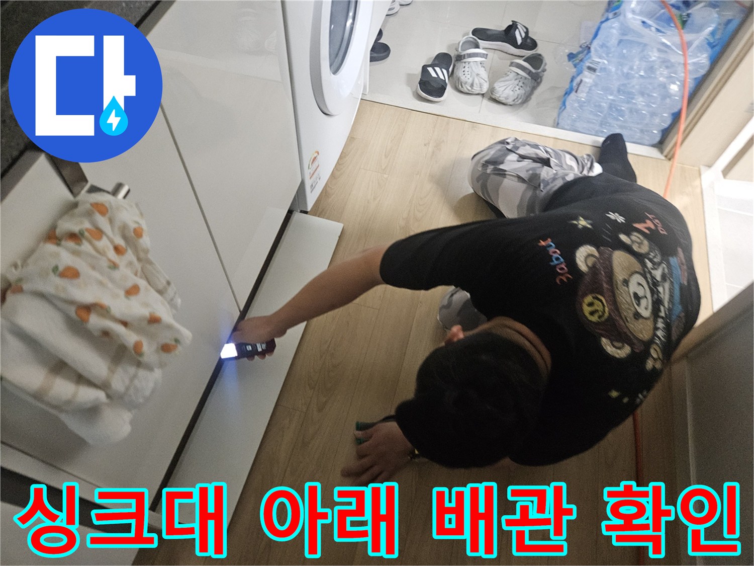 싱크대-하부장-배관-상태를-손전등으로-살펴보는-모습