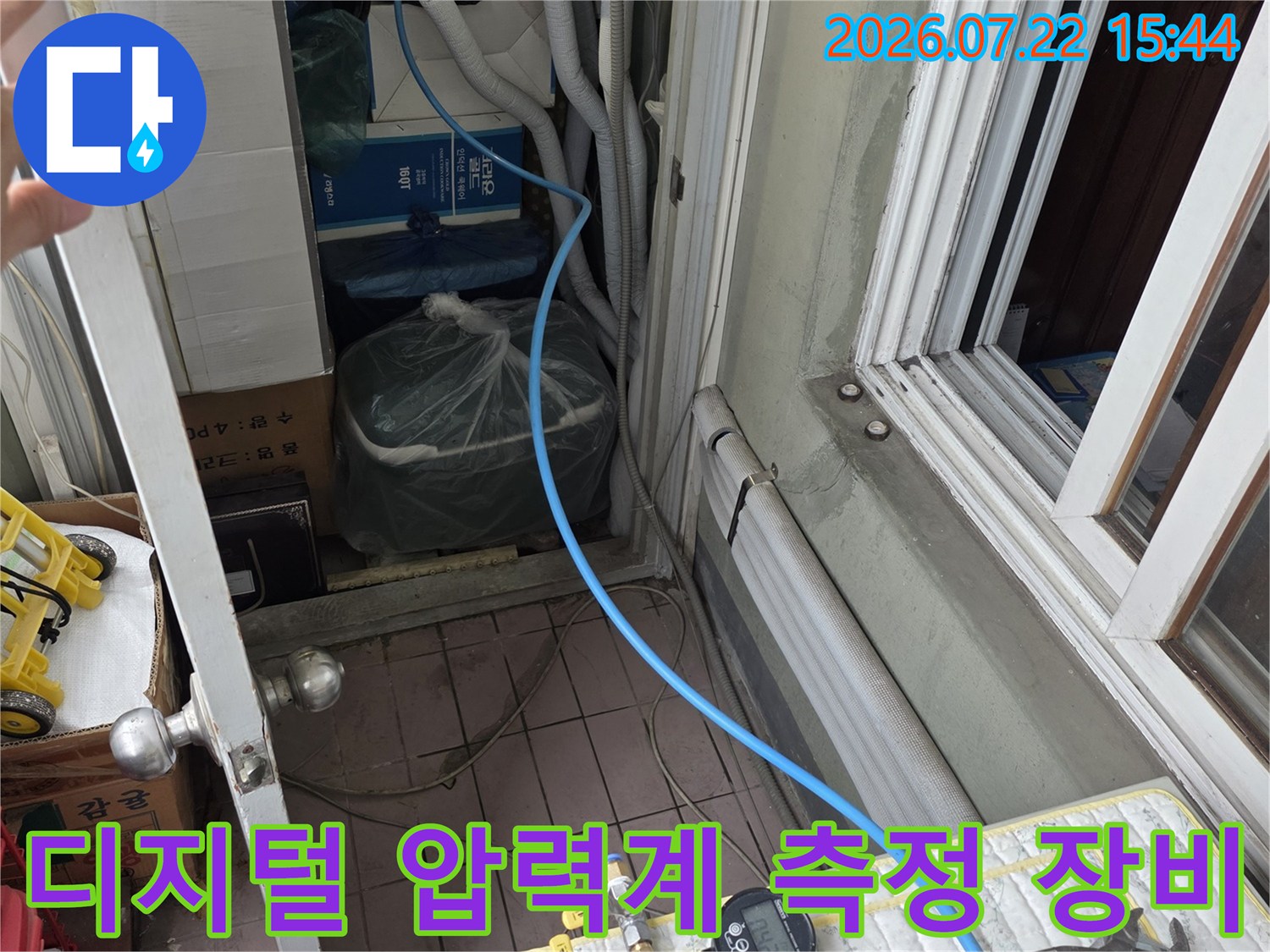 흰색 패드 위에 놓인 누수 탐지용-압력 게이지와 파란색 연결 호스