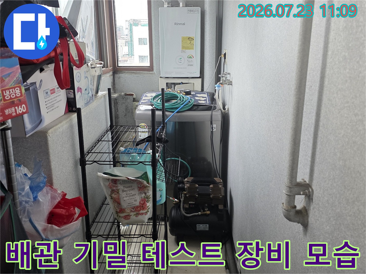 보일러실 하단 선반 아래에 설치된 검정색 콤프레샤와 파란색 연결 호스