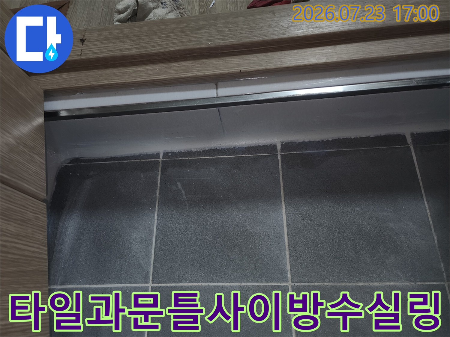 회색-욕실-타일-위에-나무-문턱이-놓여있고-그-사이가-실리콘으로-메워진-상태